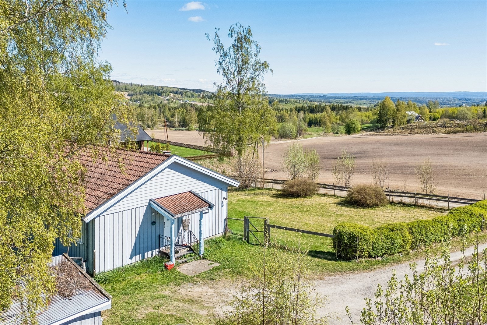 Tomten er opparbeidet med plen og variert beplantning, med gruset innkjøring og parkering. Galleribilde