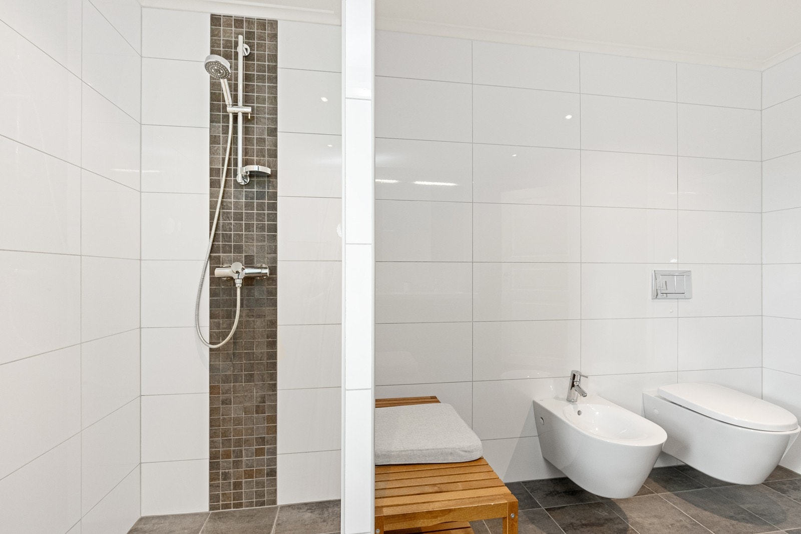 Badet er utstyrt med dusjhjørne, vegghengt toalett og bide. Galleribilde