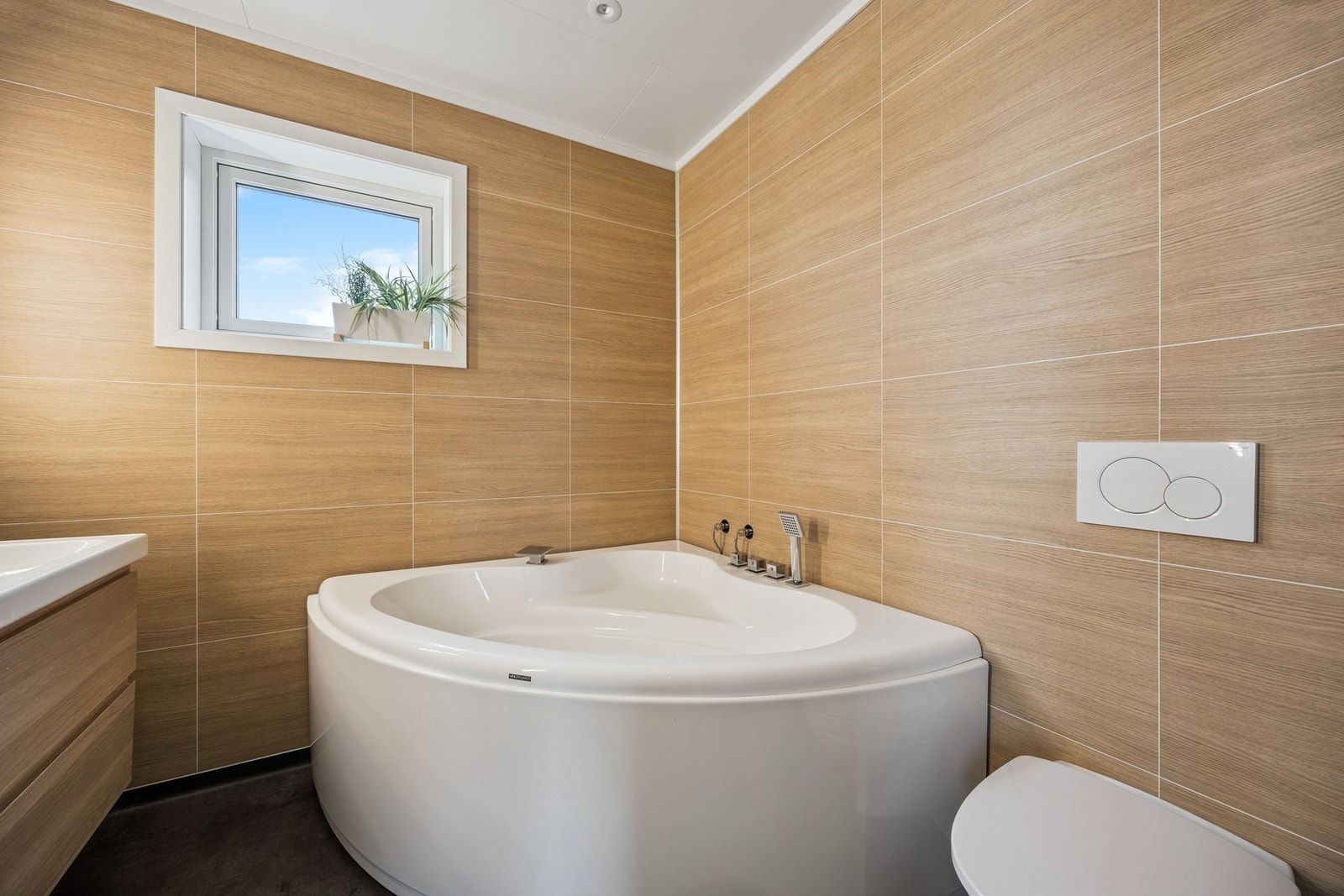 Badet er innredet med dobbel servant, badekar og toalett Galleribilde