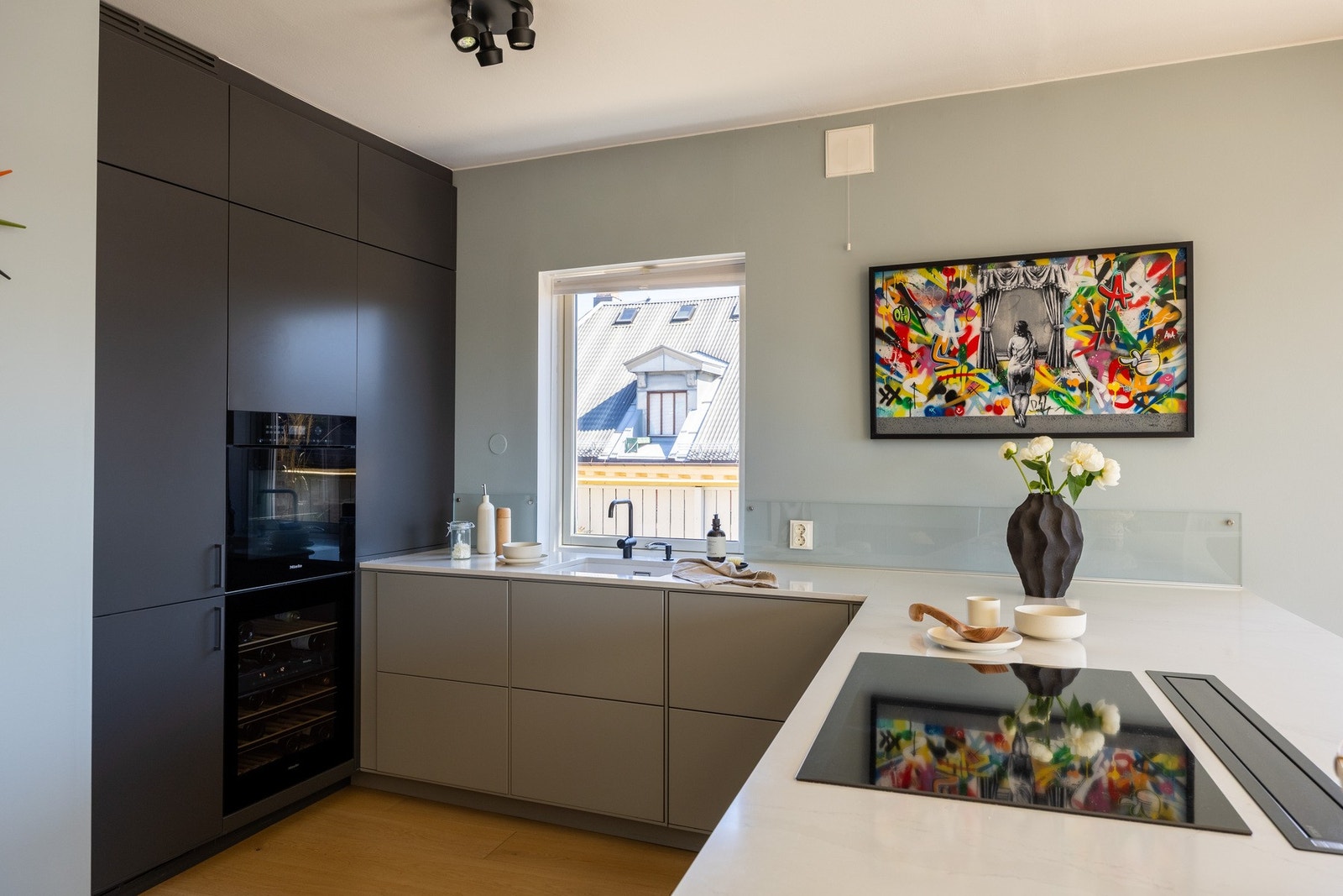 Moderne kjøkkeninnredning fra 2017 med mørke glatte fronter og benkeplate i steinkompositt. Galleribilde