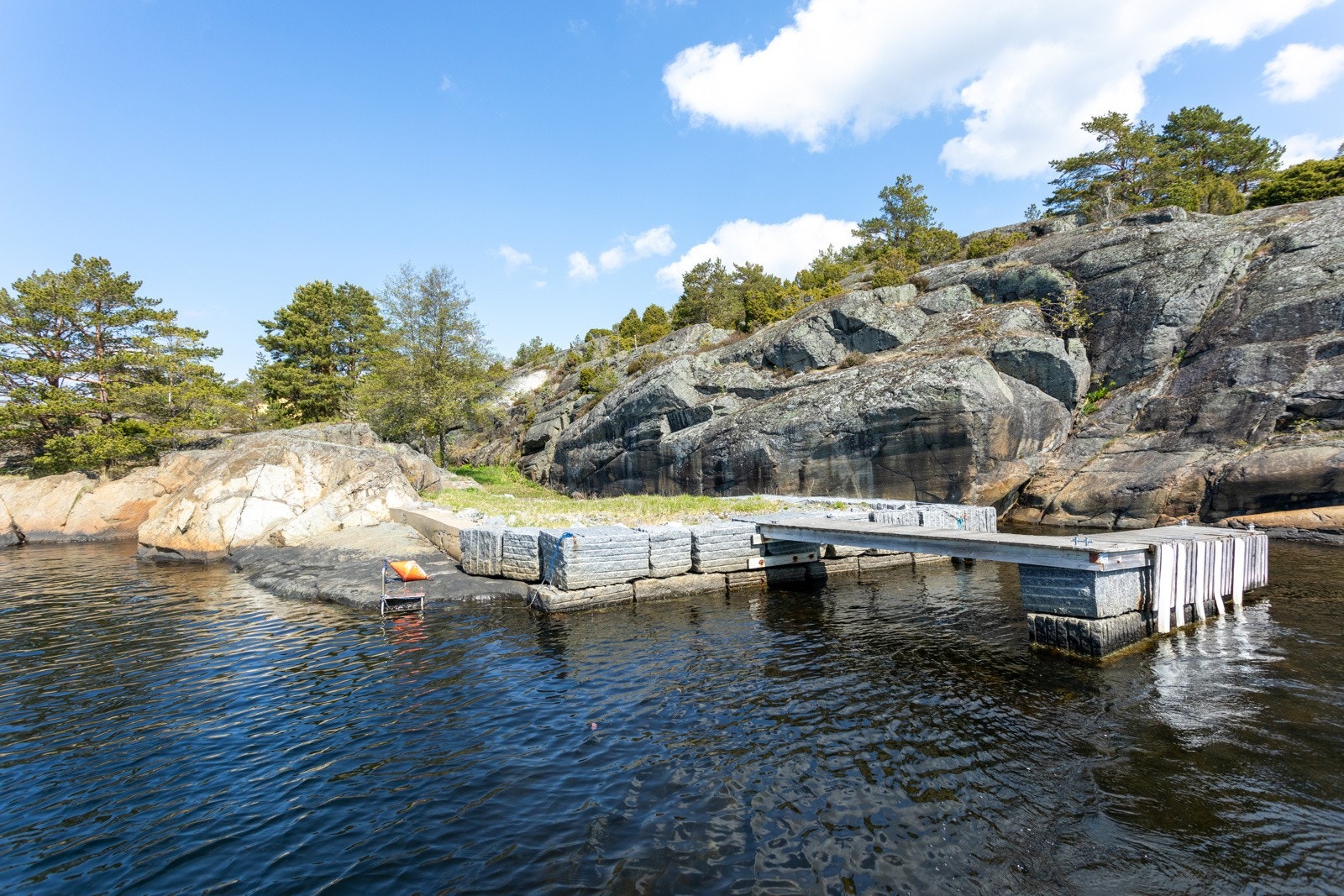 Solid steinbrygge. Sandstranden ligger lunt på innsiden av bryggen. Galleribilde