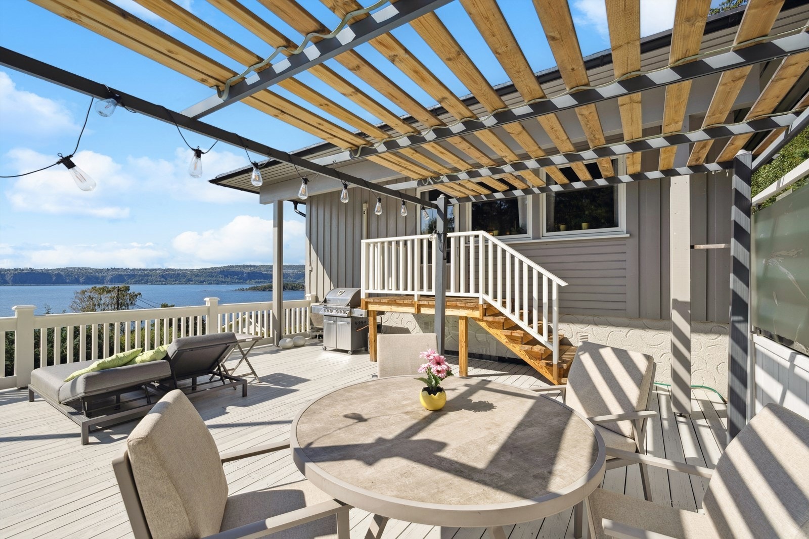 Uteplassen har dekke av treverk, hvitmalt rekkverk og en pergola. Galleribilde