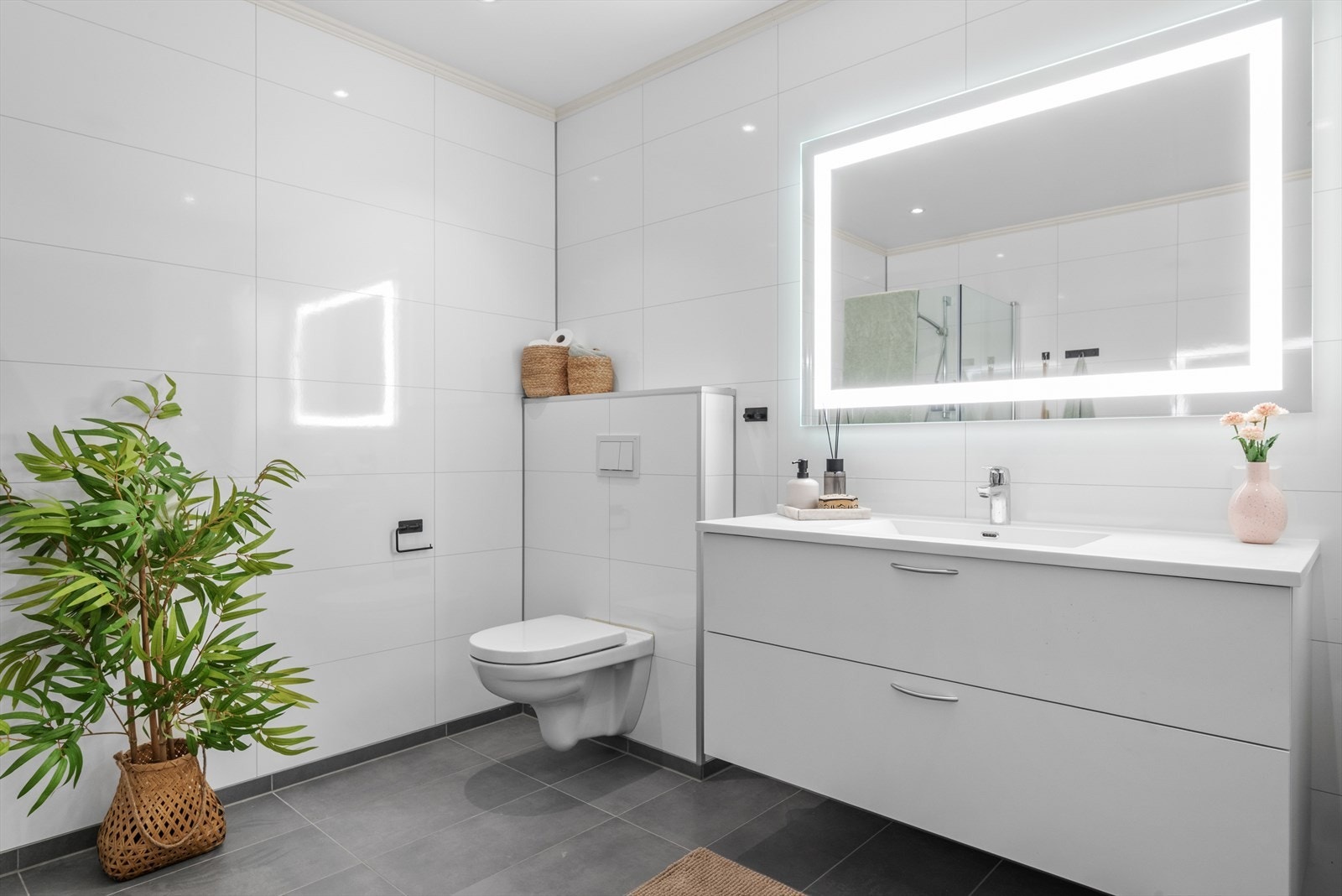 Her er det lagt vekt på kvalitet i alle detaljer med flislagt gulv, gulvvarme, downlights og moderne innredning som innfellbare dusjdører, veggmontert wc, stort speil med integrert belysning og et stilrent servantskap. Galleribilde