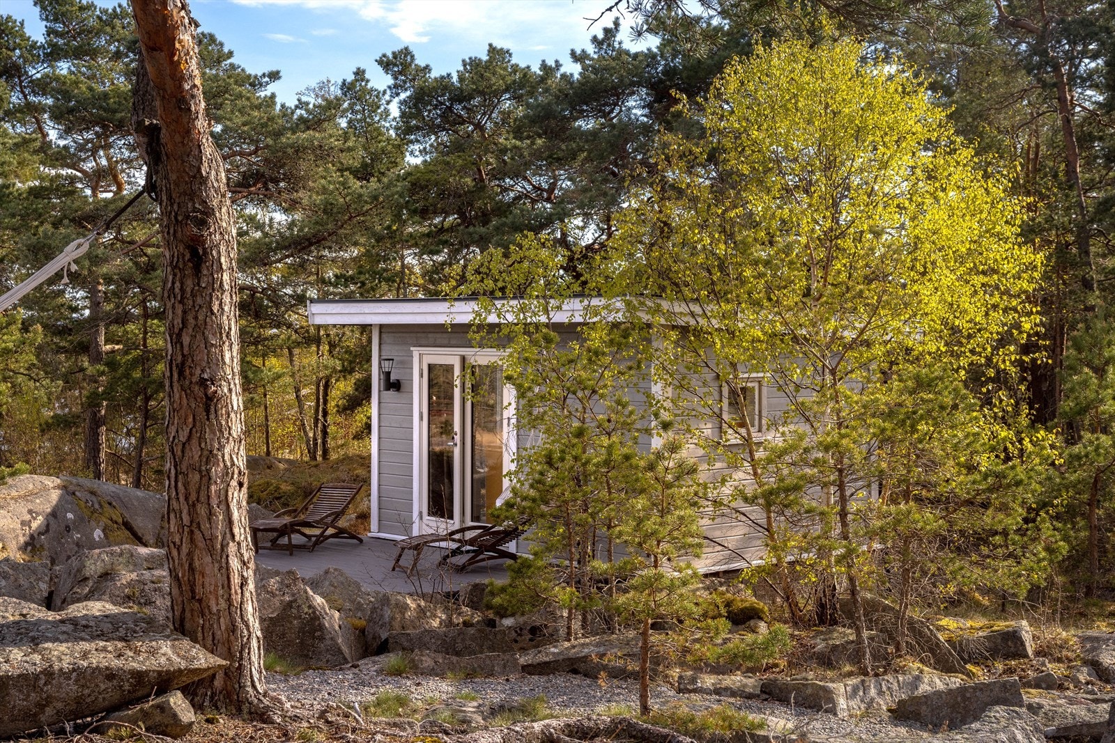 Bortenfor boligen ligger et anneks for gjester med både vinduer og terrassedører med glass og en egen platting. Galleribilde