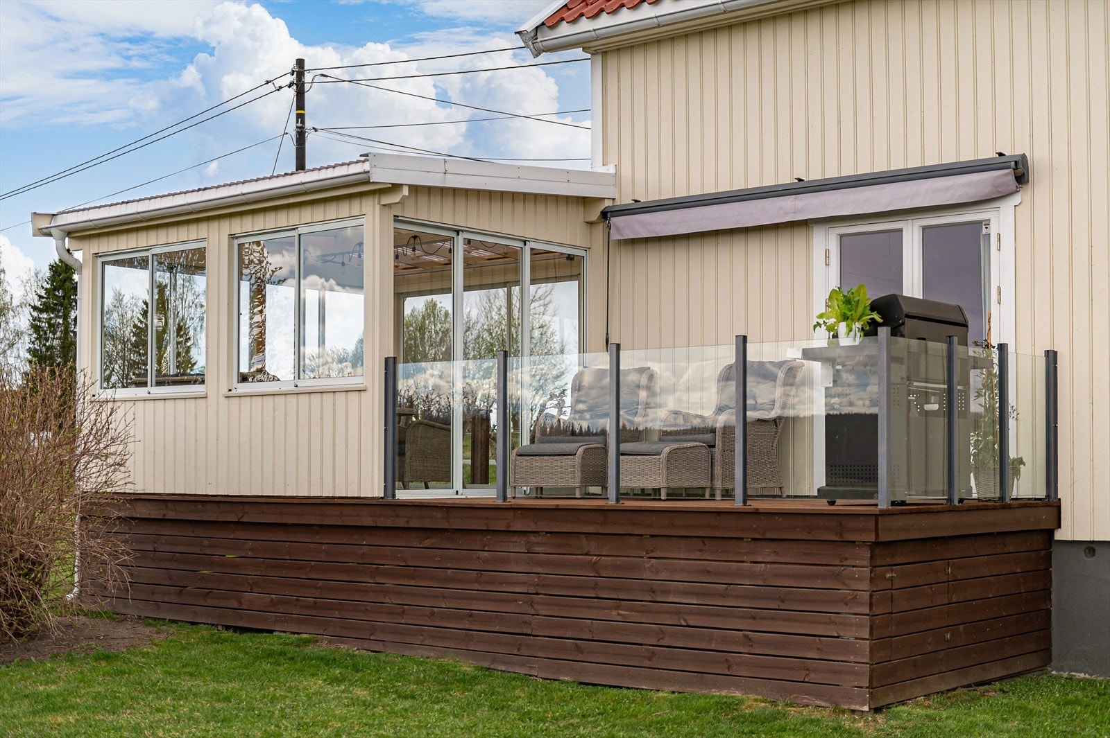 Terrasse med glassrekkverk og terrassemarkise. Galleribilde