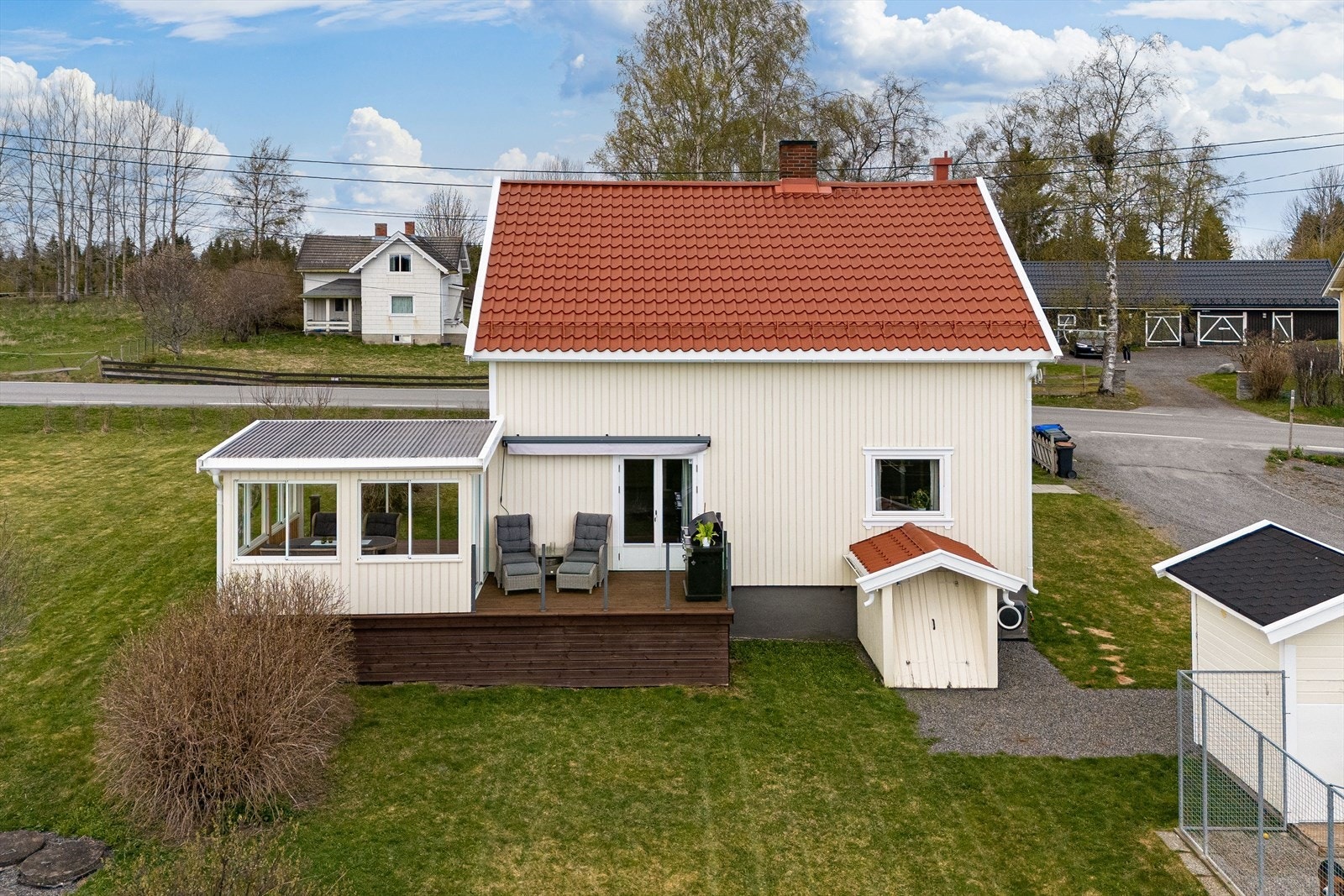 Boligens fasade med kjellernedgang, beplantninger og busker samt hagestue. Galleribilde