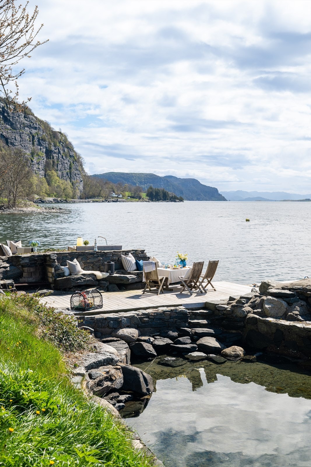 Stemningsfull uteplass helt i vannkanten med lune soner og utsikt mot fjord og fjellandskap. Galleribilde