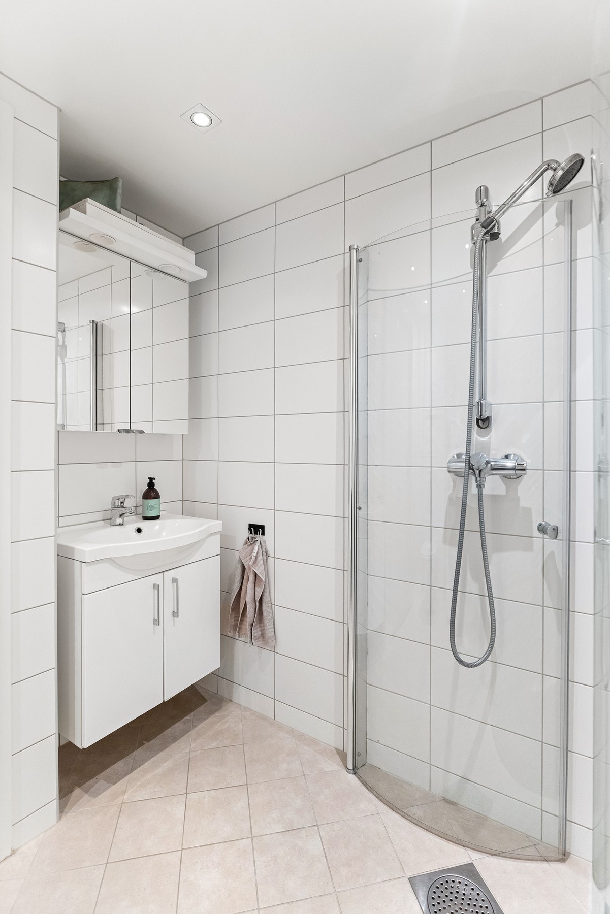 Badet er utstyrt med vegghengt toalett, opplegg for vaskemaskin og vegghengt servantskap med overhengt speil. I dusjhjørnet er det montert plassbesparende dusjdører av glass. Galleribilde