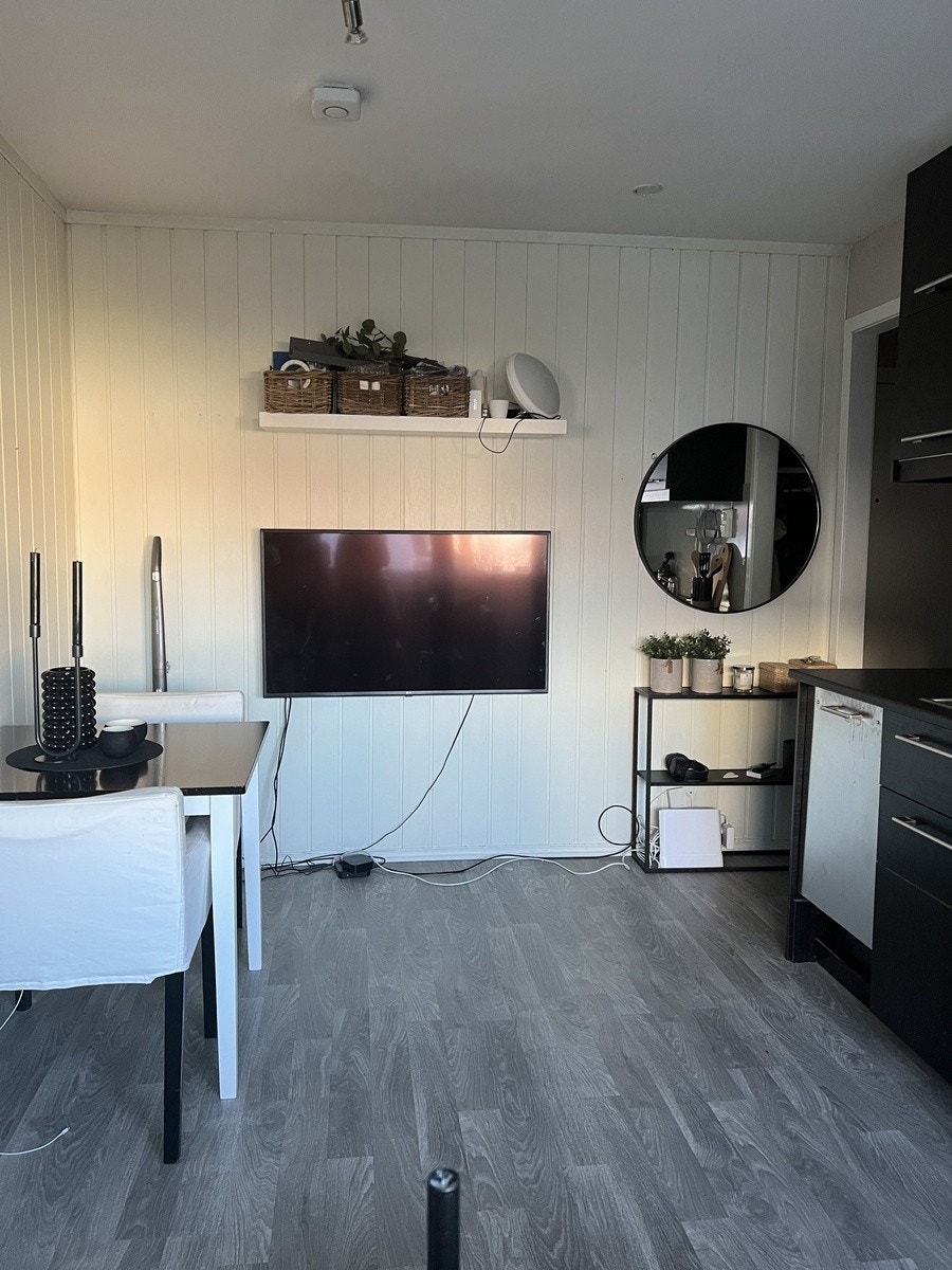 Stua/kjøkkenet sett fra sofaen. Stor TV, speil og spisebord. Galleribilde