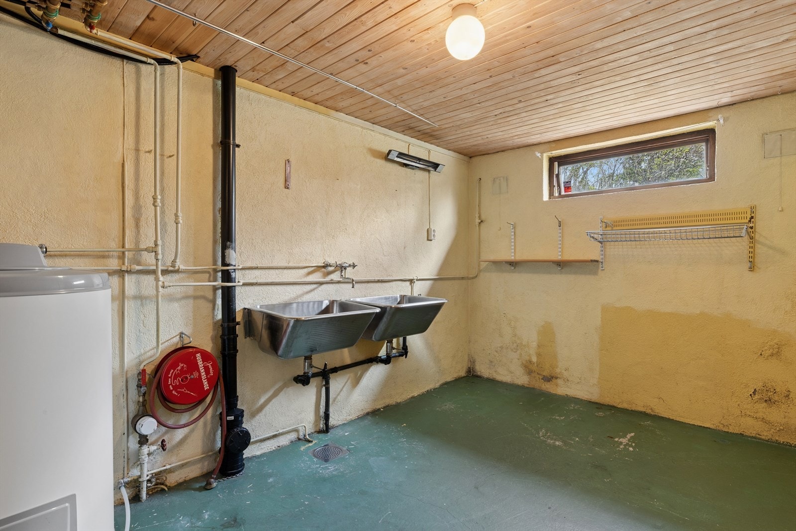 Vaskerom fra byggeår med betonggulv og malte betongvegger. Rommet har opplegg for vaskemaskin, to utslagsvasker og sluk fra byggeår. Galleribilde