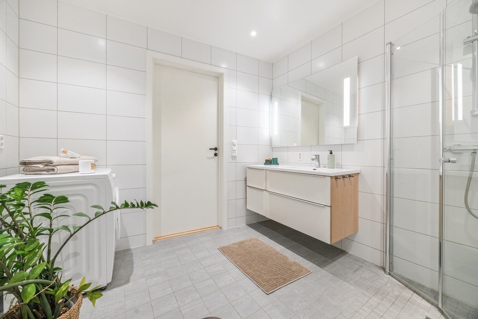 Badet er utstyrt med servant med underskuffer, dusjhjørne, vegghengt toalett og opplegg for vaskemaskin. Galleribilde