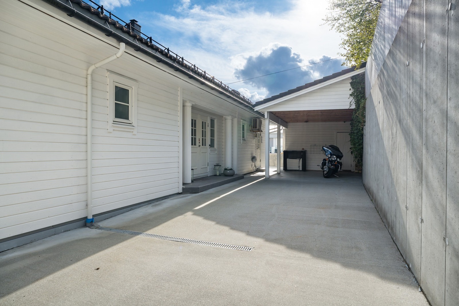Tomten er svært flott opparbeidet og har rikelig med parkeringsmuligheter. Carport like ved boligens inngangsparti. Det er lagring i bakkant, samt en egen praktisk inngang til vaskerom Galleribilde