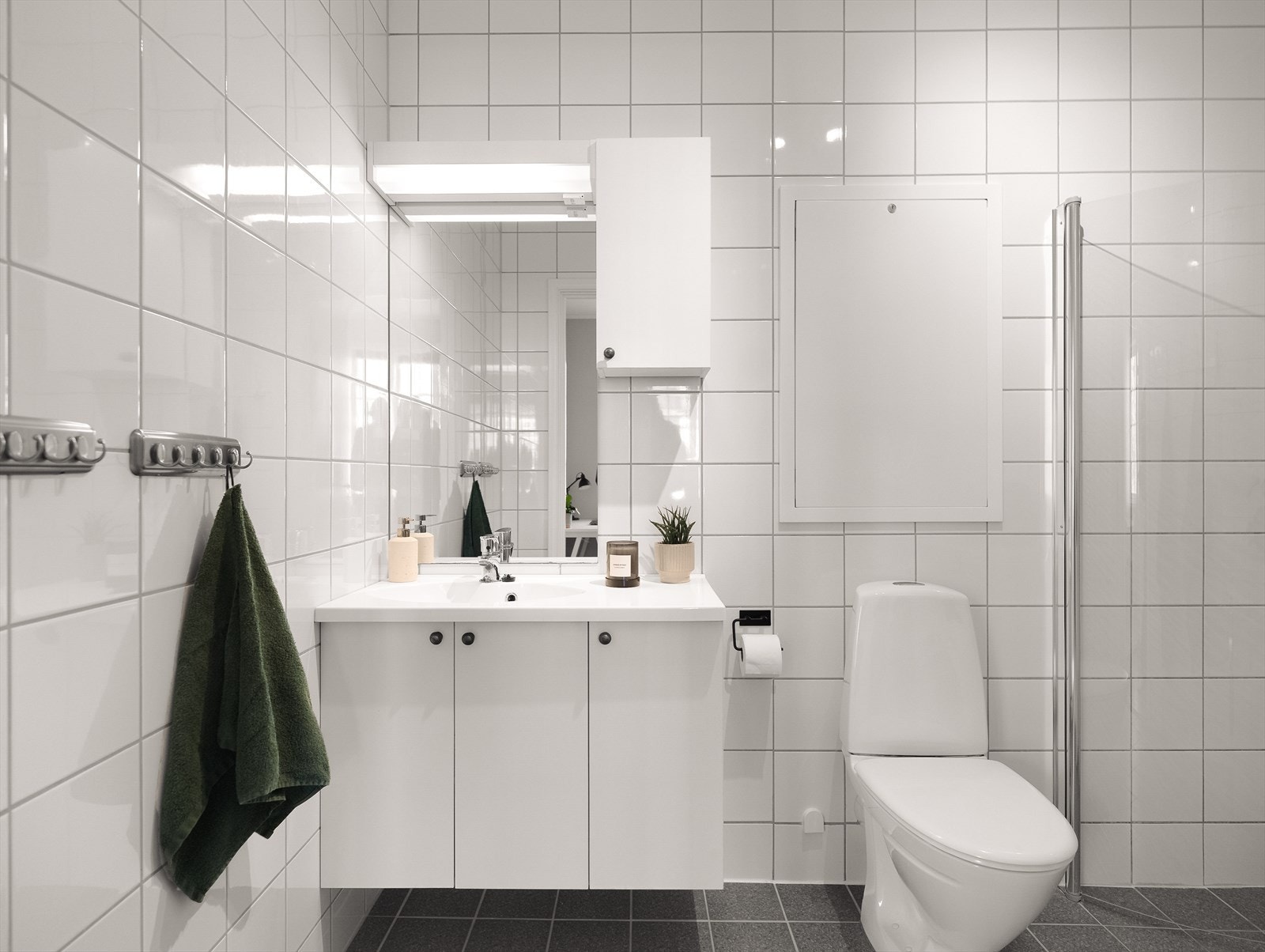 Leilighetens bad har flislagte overflater, servant med underskap og god belysning. Galleribilde
