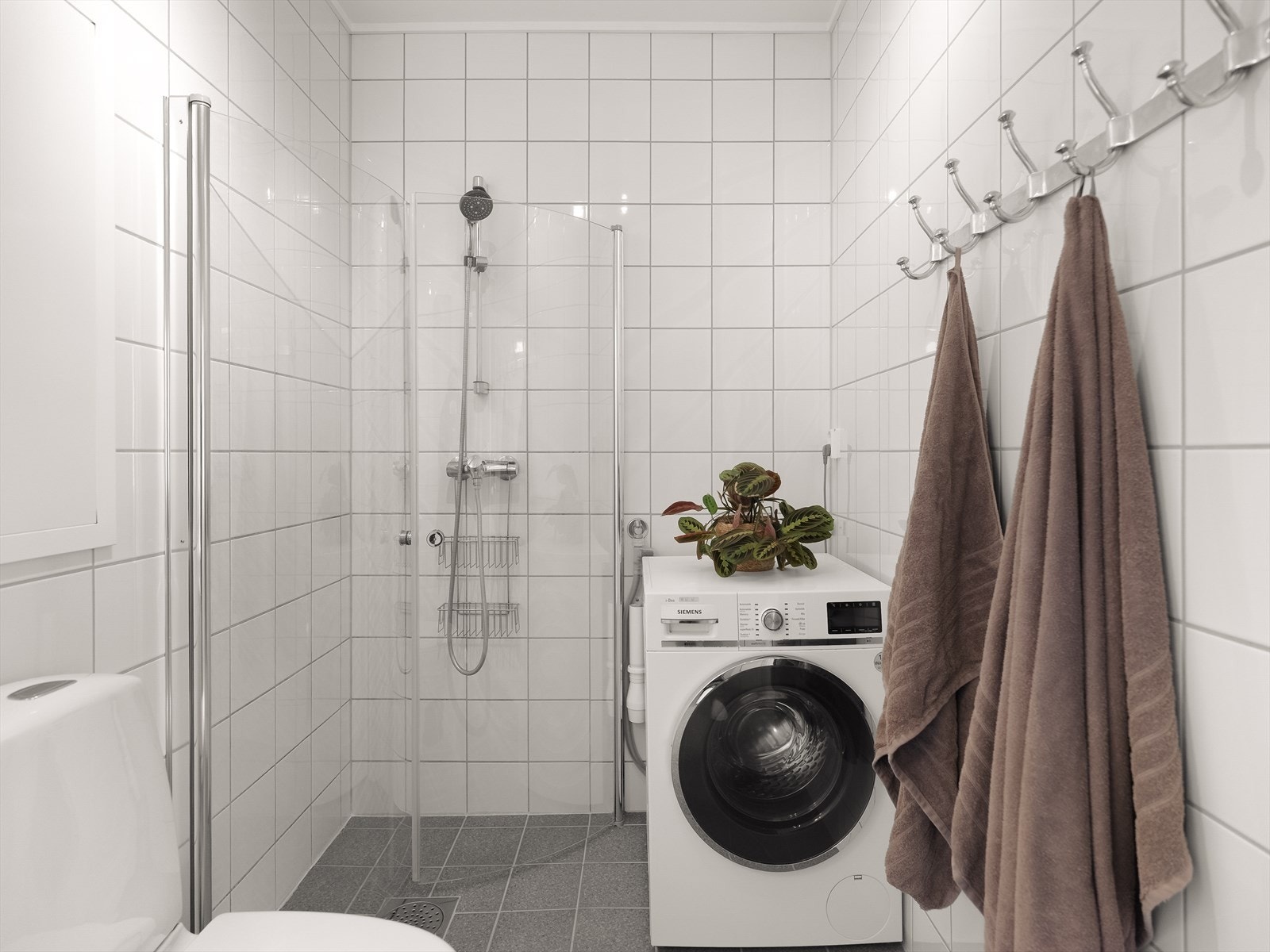 Badet er videre utstyrt med dusjhjørne med innfellbare glassdører og opplegg for vaskemaskin. Galleribilde