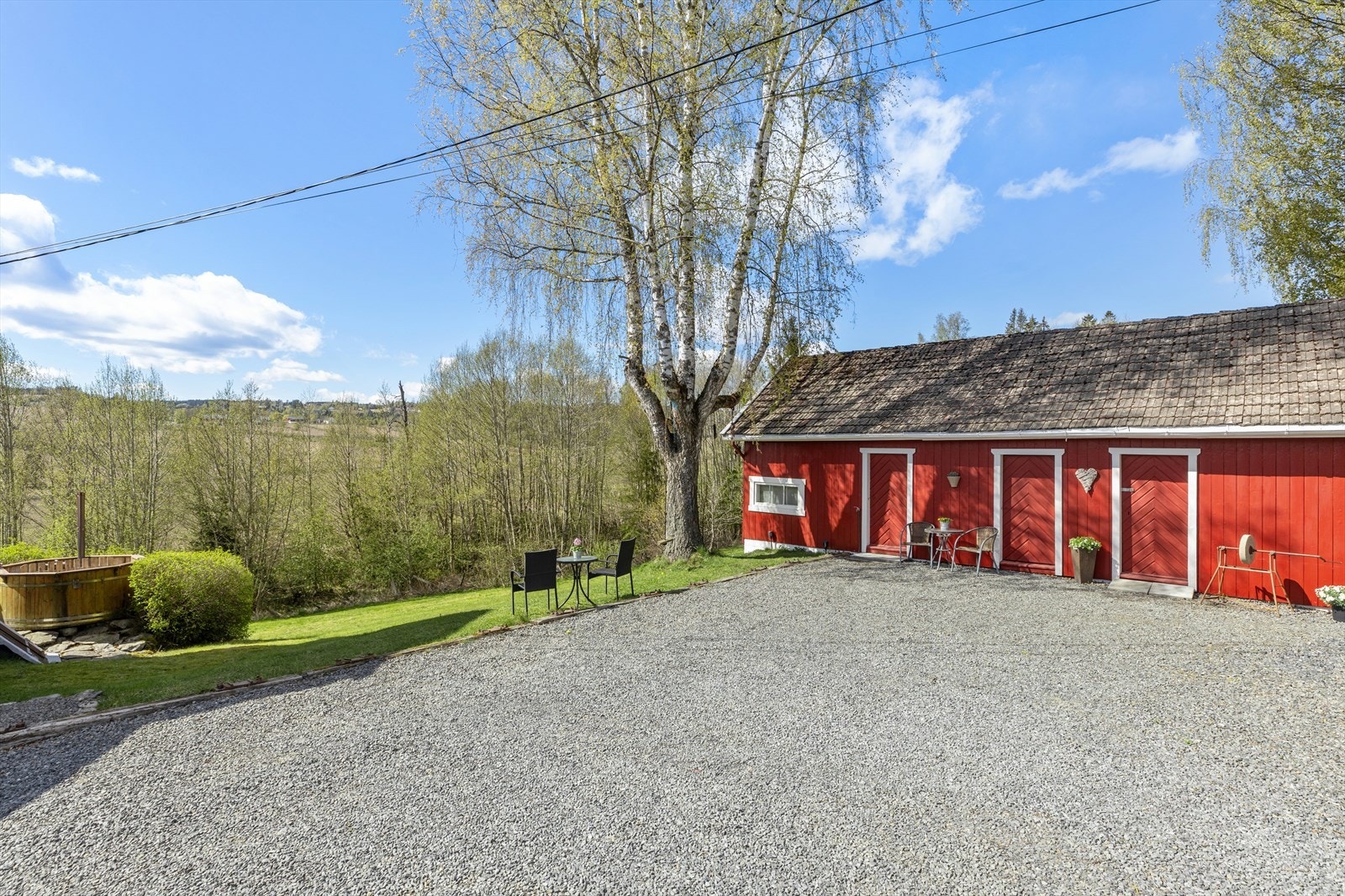 Stor, gruset gårdsplass med carport for to biler og et romslig uthus. Galleribilde