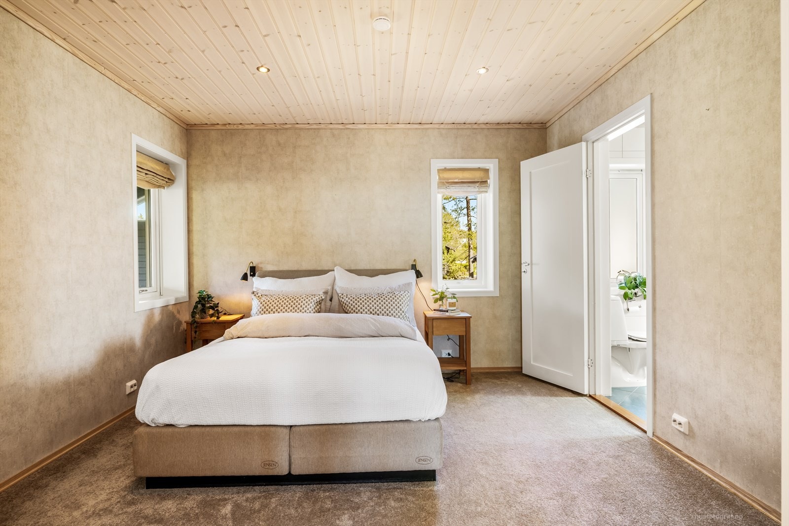 Elegant hovedsoverom med vegg til vegg teppe på gulv og en pen tapet på gulv. Hovedsoverommet har direkte tilknytning til eget bad. Galleribilde