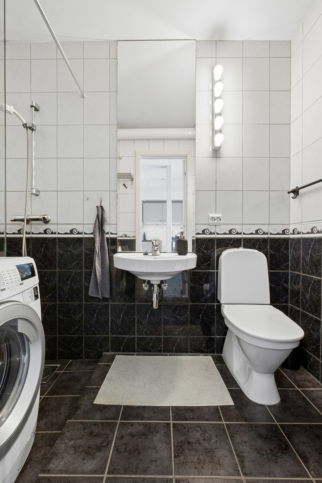 Badet har flislagt gulv, baderomsinnredning og opplegg for vaskemaskin. Galleribilde