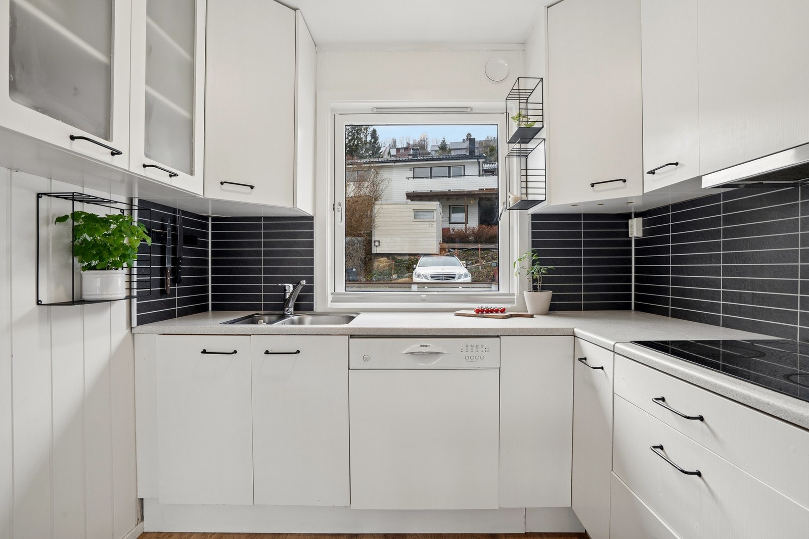 Innredning med slette fronter, laminert benkeplate og kitchenboard på veggen over benken. Galleribilde