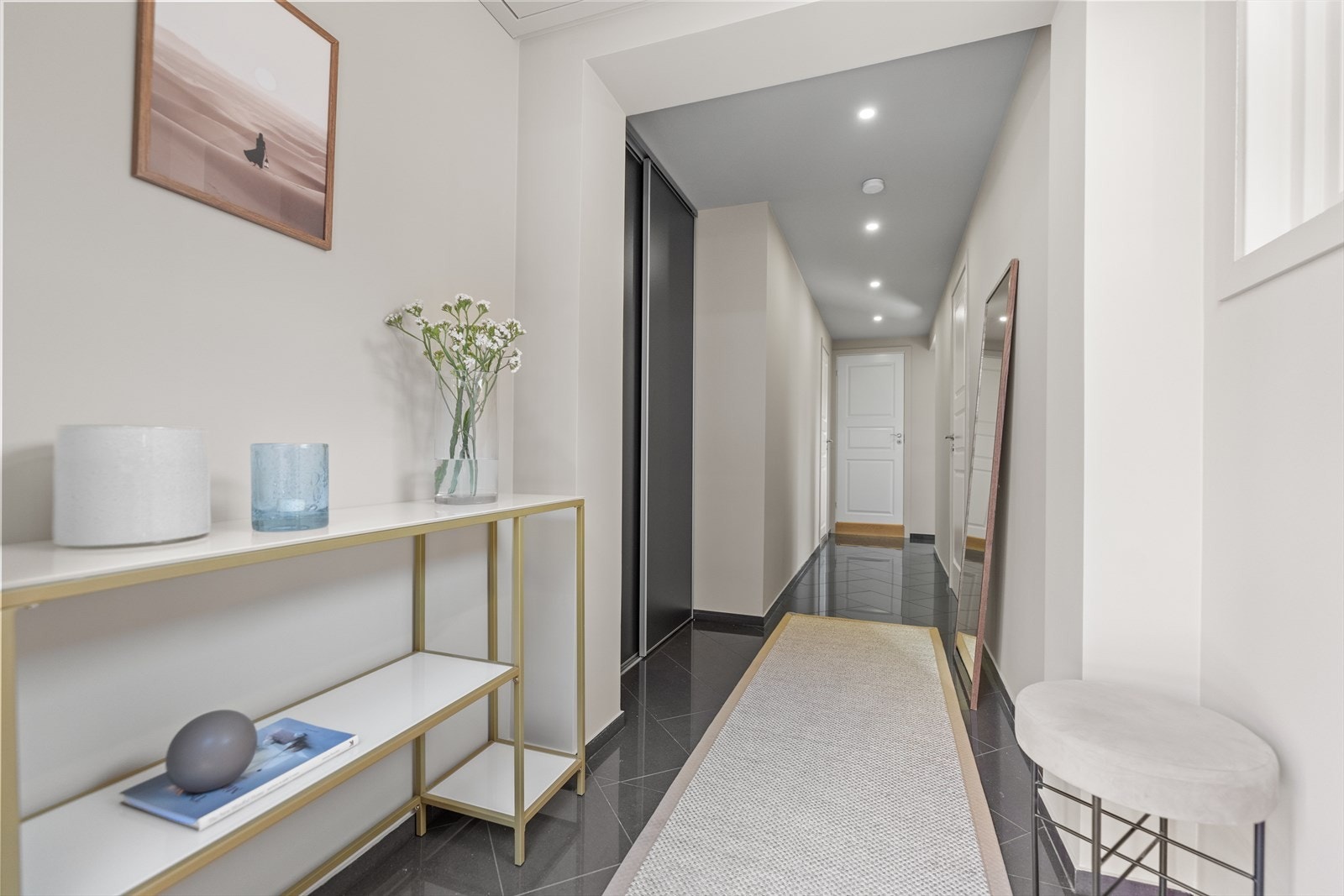 Gangen har et praktisk flislagt gulv som er slitesterkt og enkelt å holde rent, og er utstyrt med innebygde skap som gir rikelig med oppbevaringsplass for yttertøy, sko og øvrige eiendeler. Galleribilde