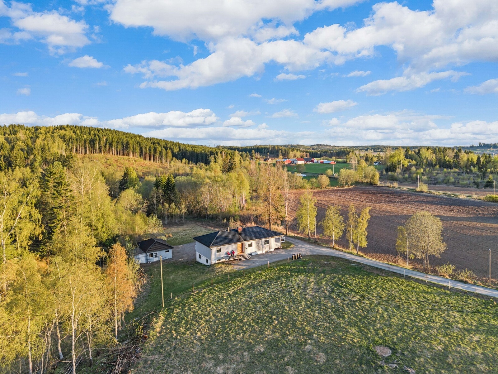 Oversiktsbilde som viser boligens naturskjønne beliggenhet med nærhet til skog, jorder og åpne landskap. Galleribilde