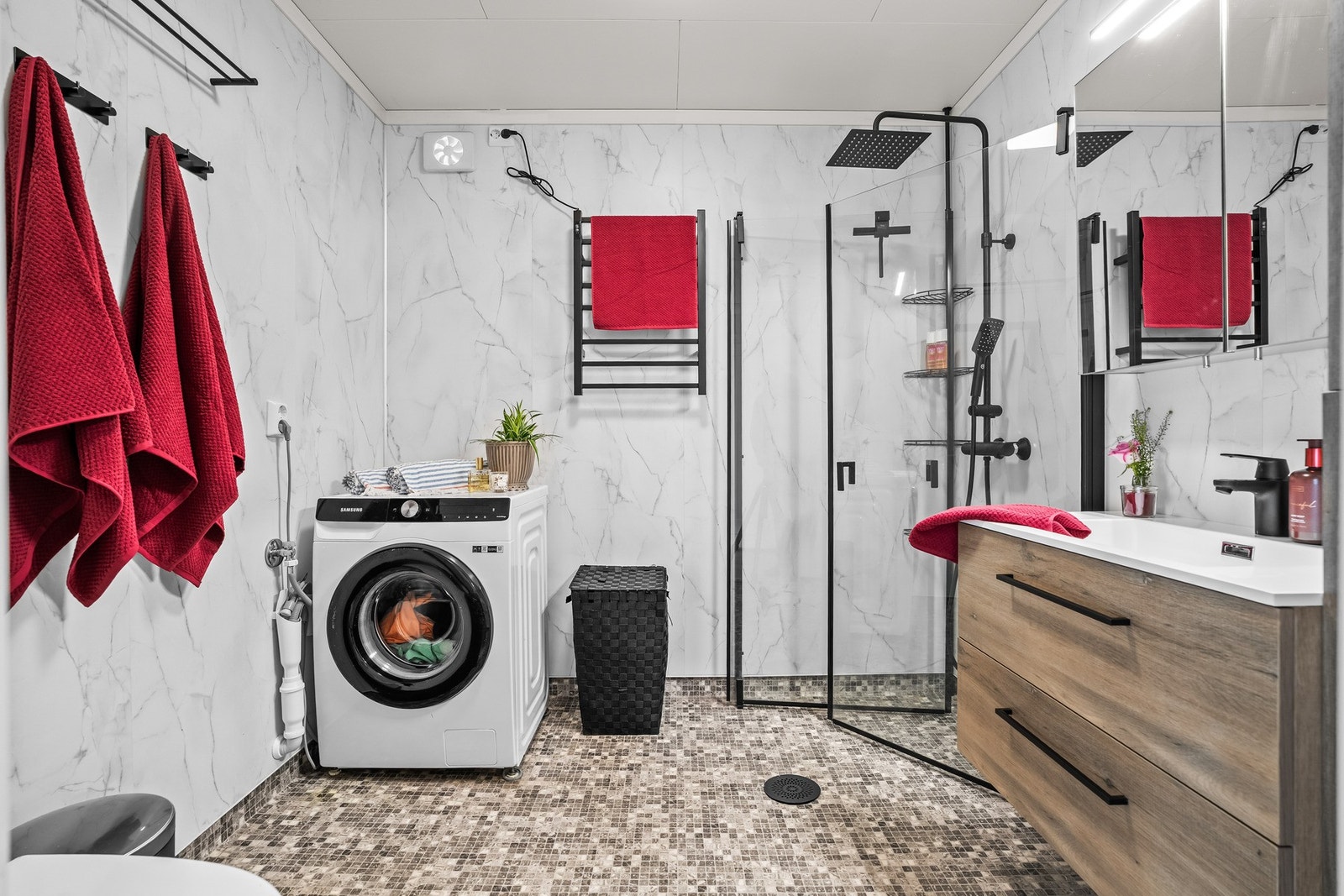 Badet er innredet med dusjhjørne med glassvegger, servant med oppbevaring og opplegg for vaskemaskin. Galleribilde