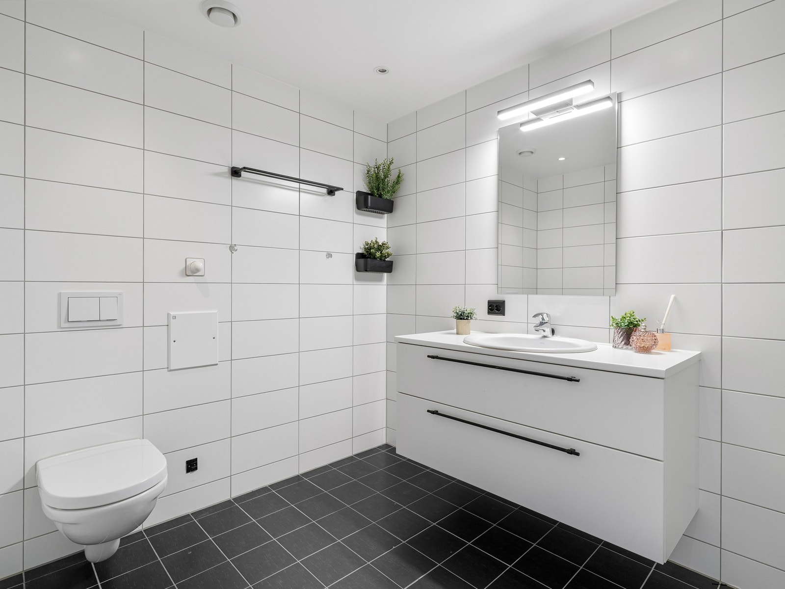 Badet er helfliset med mørke fliser på gulv og lyse fliser på veggene, samt gulvvarme. Galleribilde