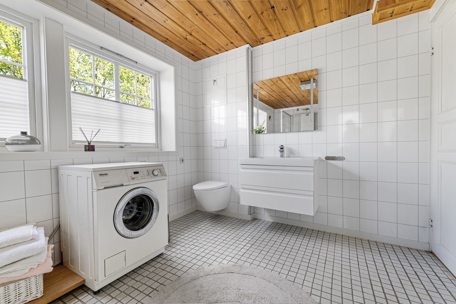 Badet er helfliset og utstyrt med vegghengt toalett og servant med skuffeløsning. Galleribilde