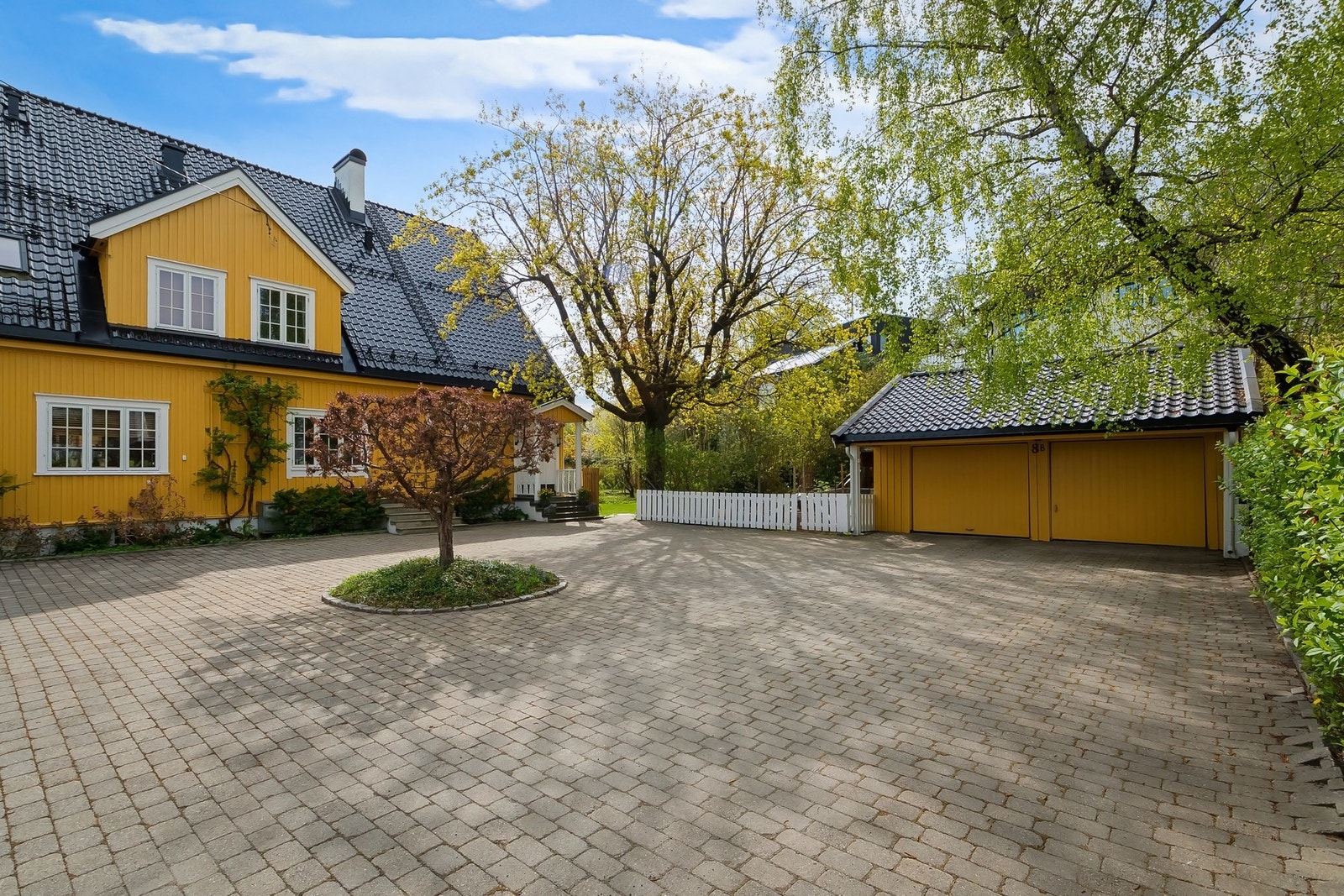 Den store, stenbelagte gårdsplassen foran huset gir et representativt førsteinntrykk og ikke minst gode parkeringsforhold, i tillegg til den separate dobbeltgarasjen. Galleribilde