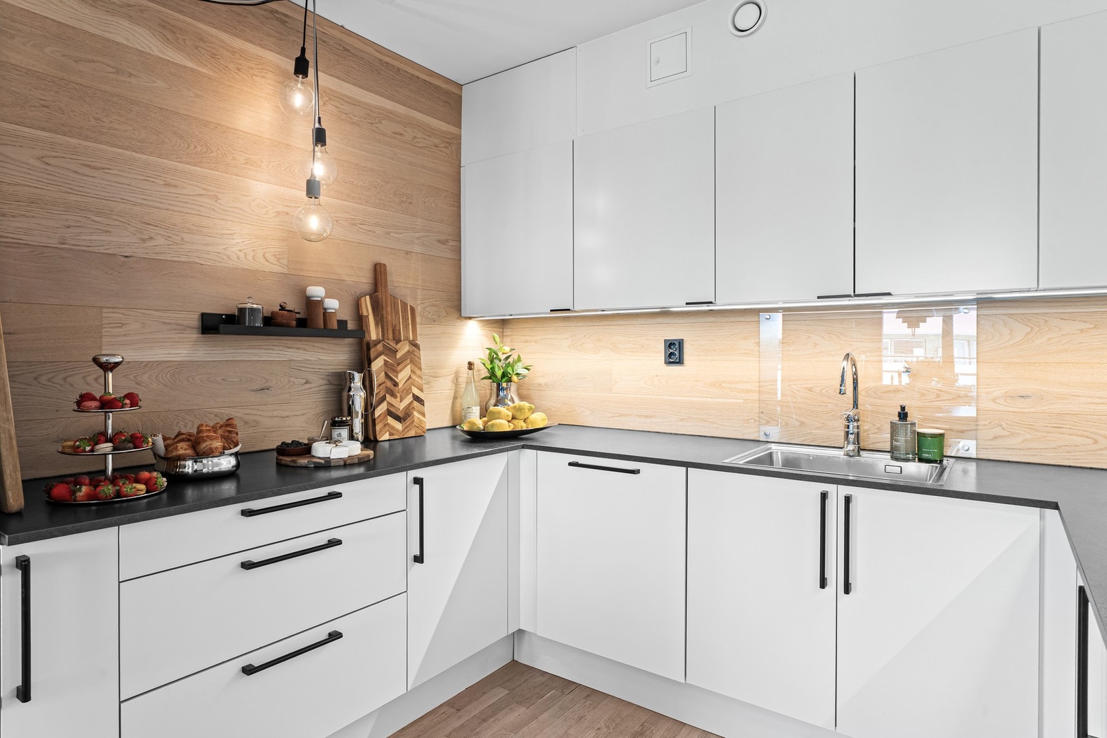 Kjøkkeninnredning fra HTH med glatte fronter, laminat benkeplate med nedfelt kum og lys under overskap. Galleribilde