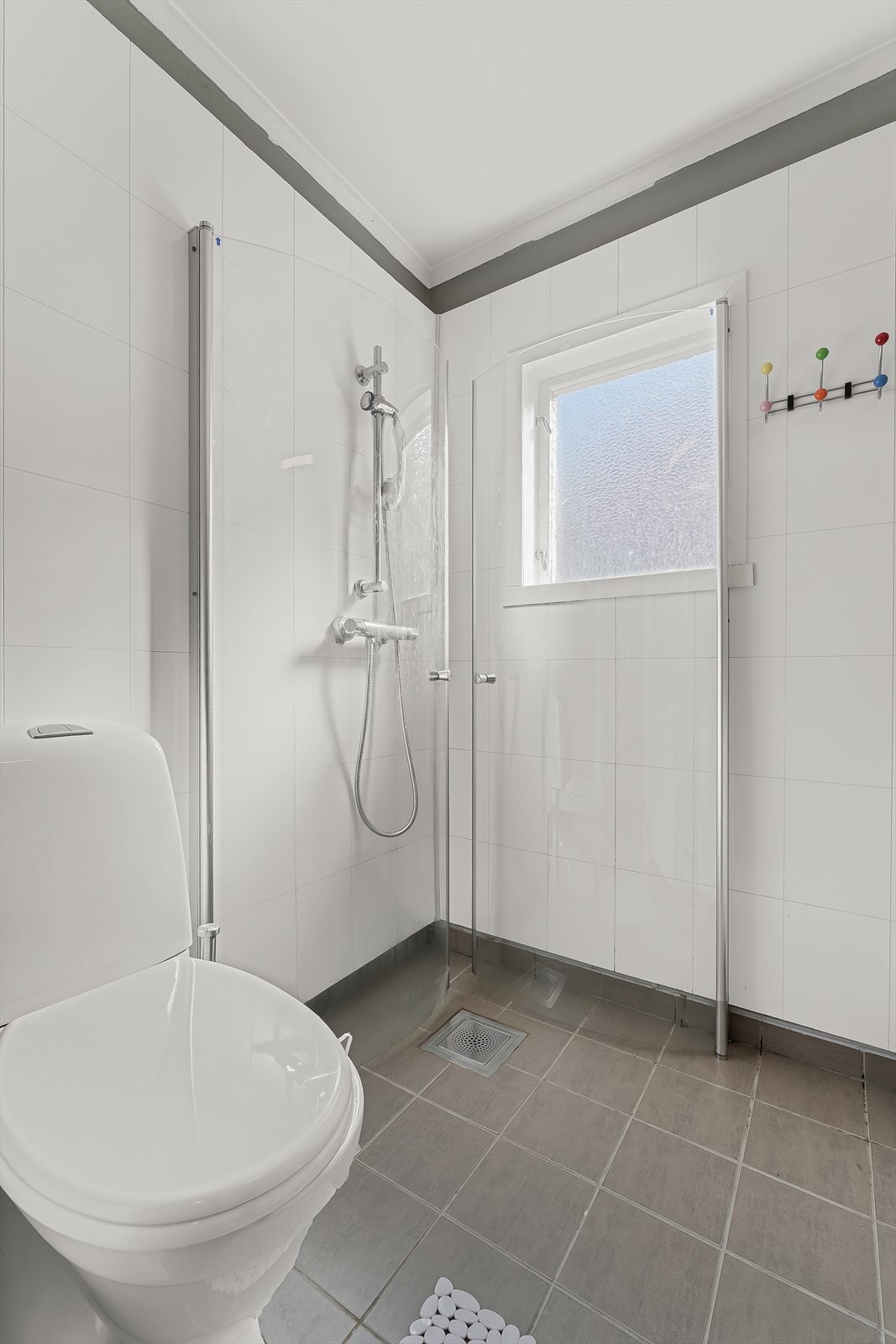 Badet er utstyrt med baderomsinnredning, gulvmontert toalett og dusjhjørne med buede dusjvegger Galleribilde