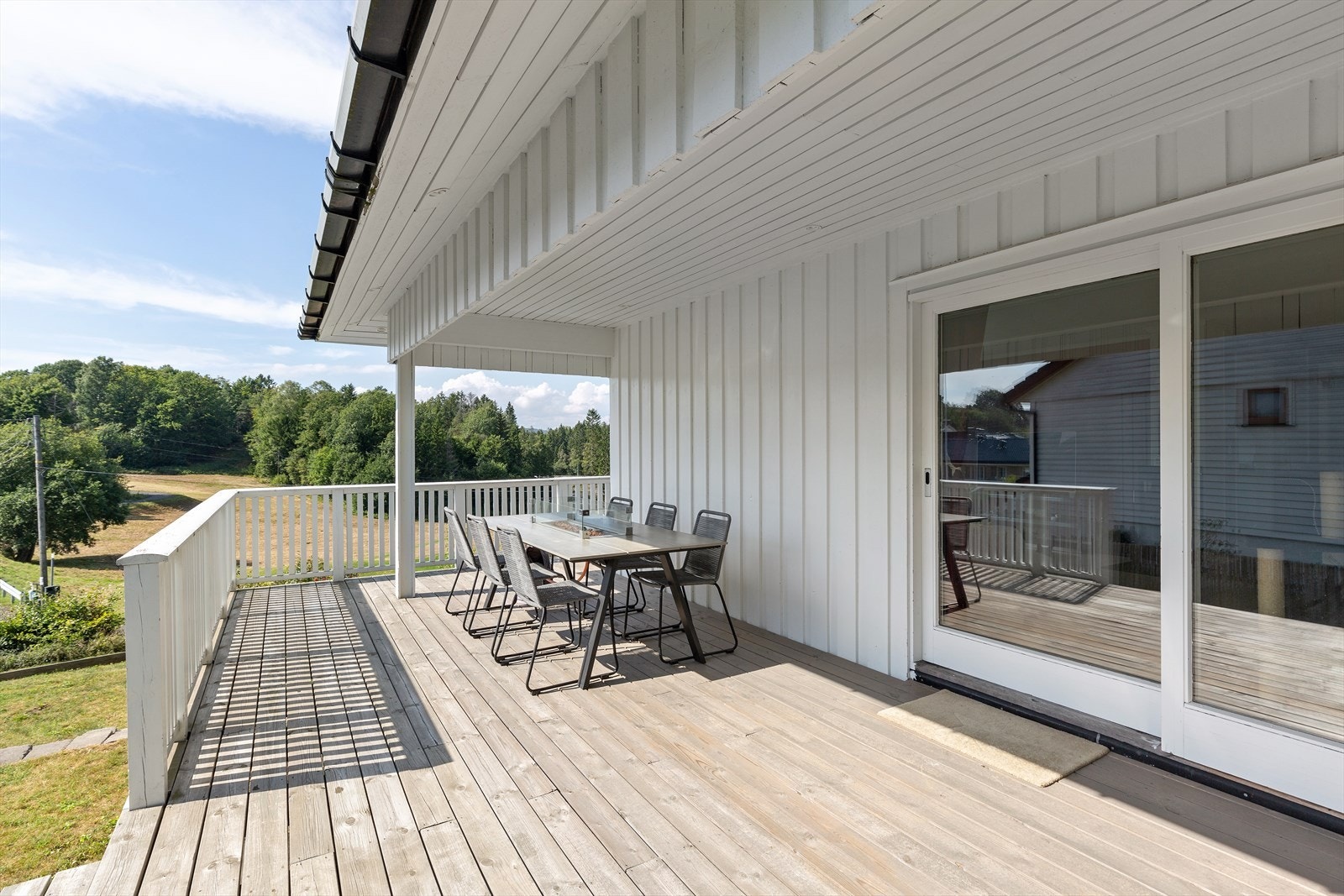 Velstelt uteområde med trapp ned til plen og stemningsfull utebelysning. Galleribilde