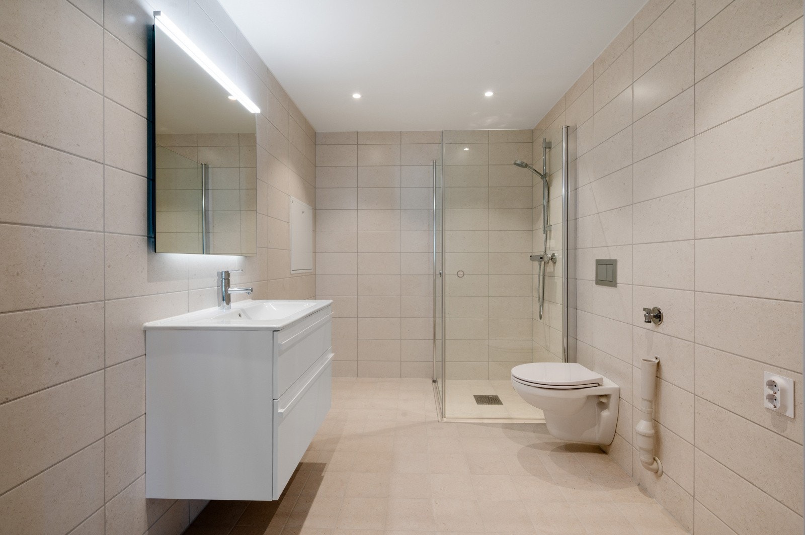 Delikat og tidløst bad i moderne jordtoner. Badet er helfliset med avsatt plass til vaskemaskin og tørketrommel. Galleribilde
