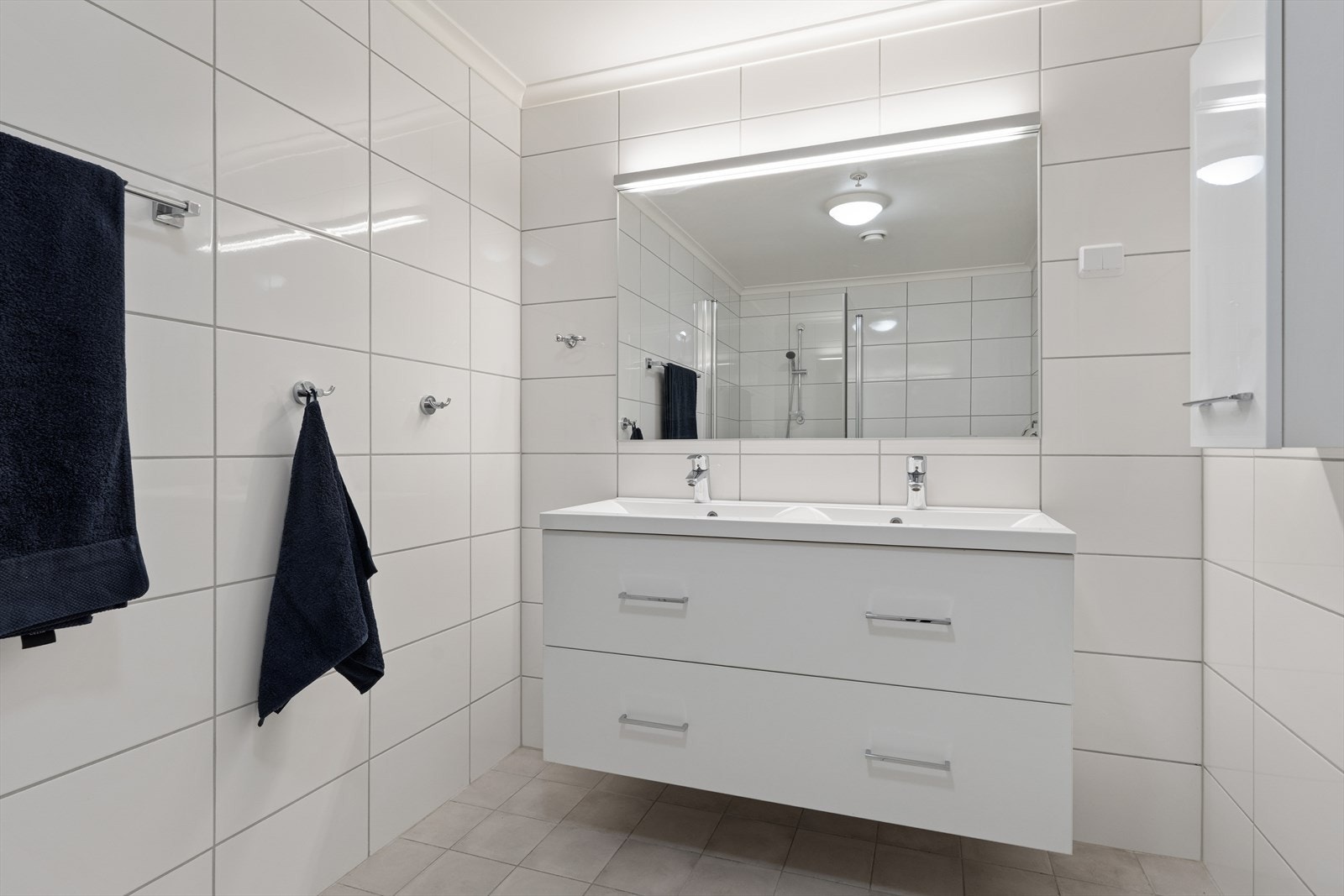 Badet tilknyttet hovedsoverommet har en bred innredning med to servanter, flislagte flater og elektriske varmekabler i gulvet. Galleribilde
