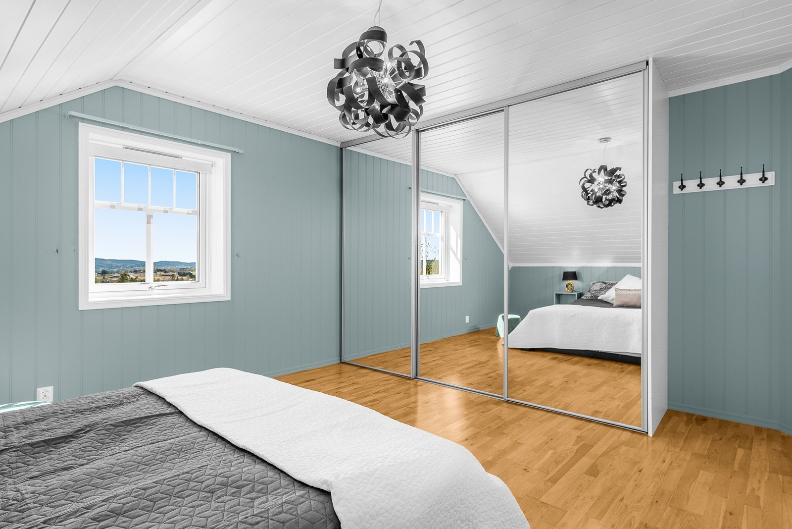 En stor skyvedørsgarderobe med speilfronter gir rikelig med oppbevaringsplass. Galleribilde