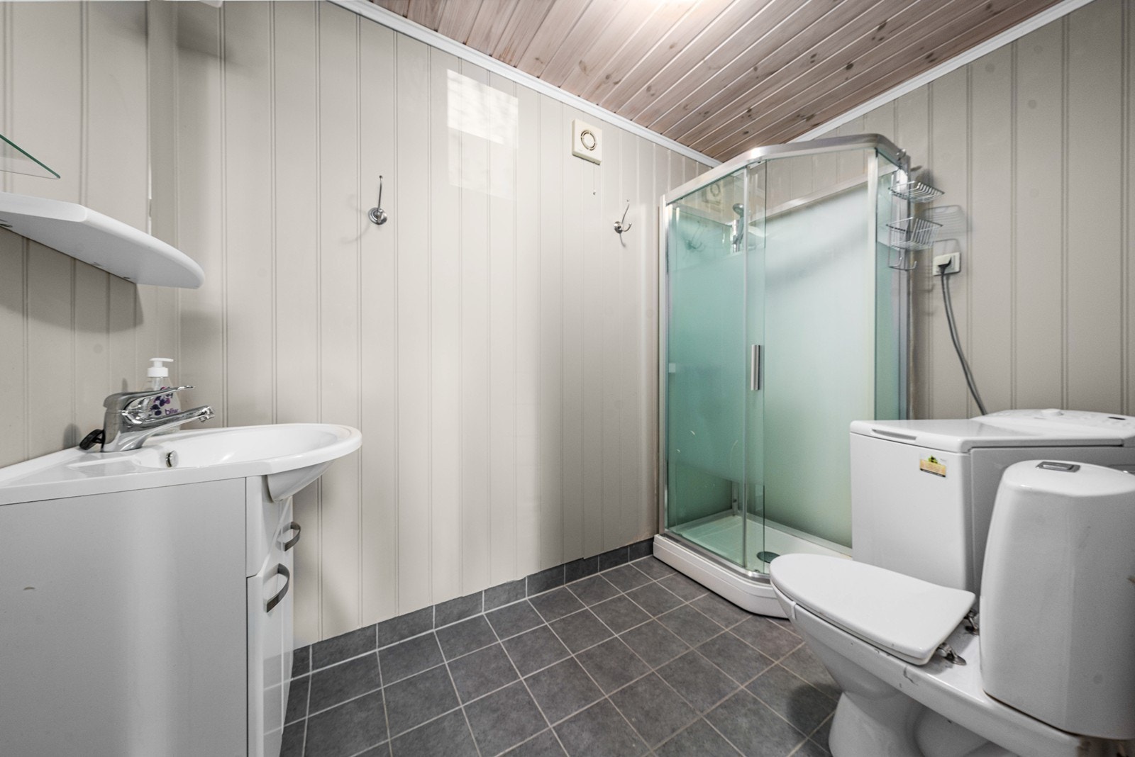 Badet i hybelen har flislagt gulv med varme, dusjkabinett og opplegg for vaskemaskin. Galleribilde
