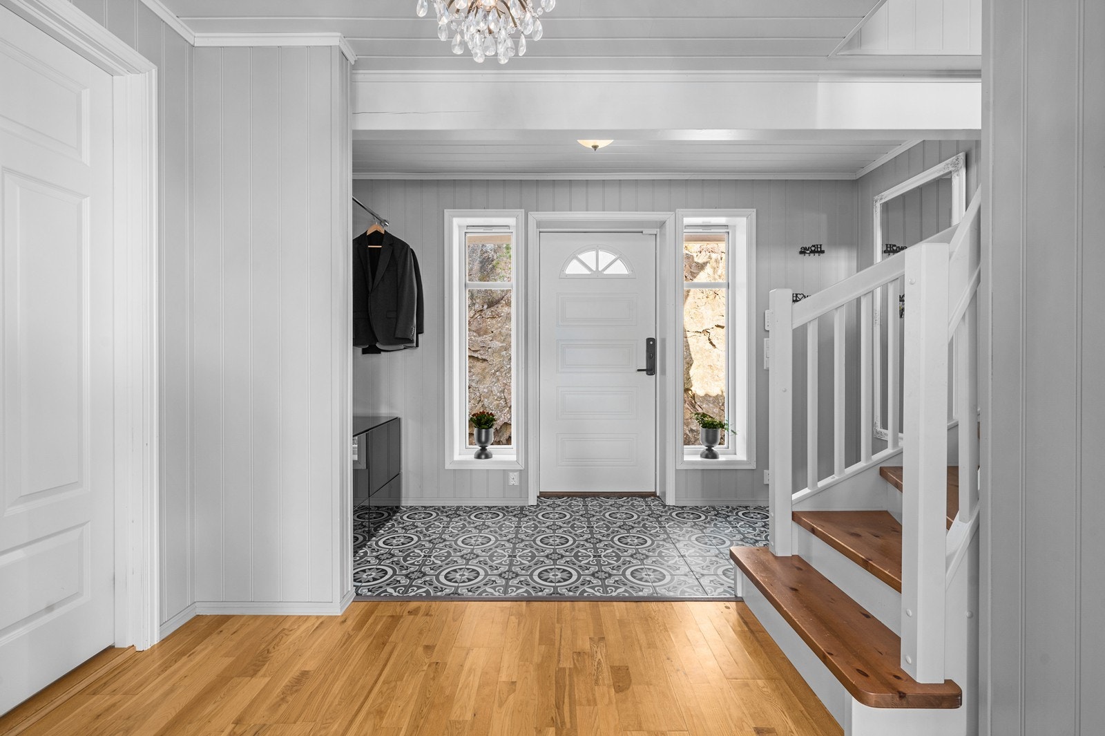 Hovedinngangen leder inn til en romslig hall. Herfra fører en malt tretrapp med lakkerte trinn opp til boligens 2. etasje. Galleribilde