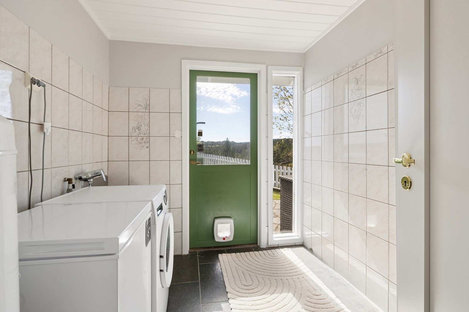 Vaskerommet i første etasje fremstår som praktisk og funksjonelt, godt tilrettelagt for hverdagens behov. Her finner man utslagsvask og opplegg for vaskemaskin. Utgangen fra rommet er en ekstra kvalitet. Galleribilde