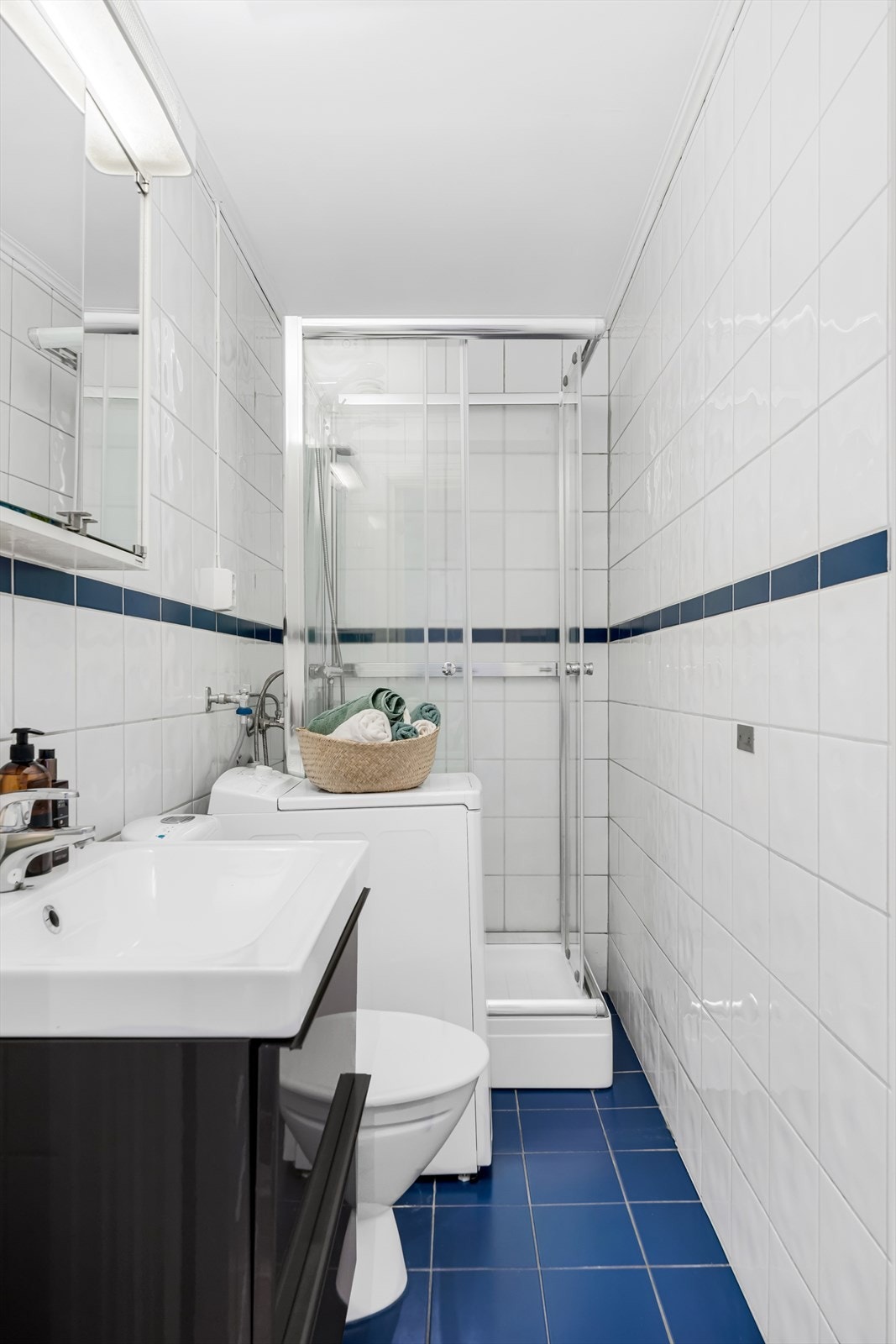 Flislagt bad på ca. 3m², som er utstyrt med veggbygd servant, toalett, opplegg for vaskemaskin og dusjkabinett. Galleribilde
