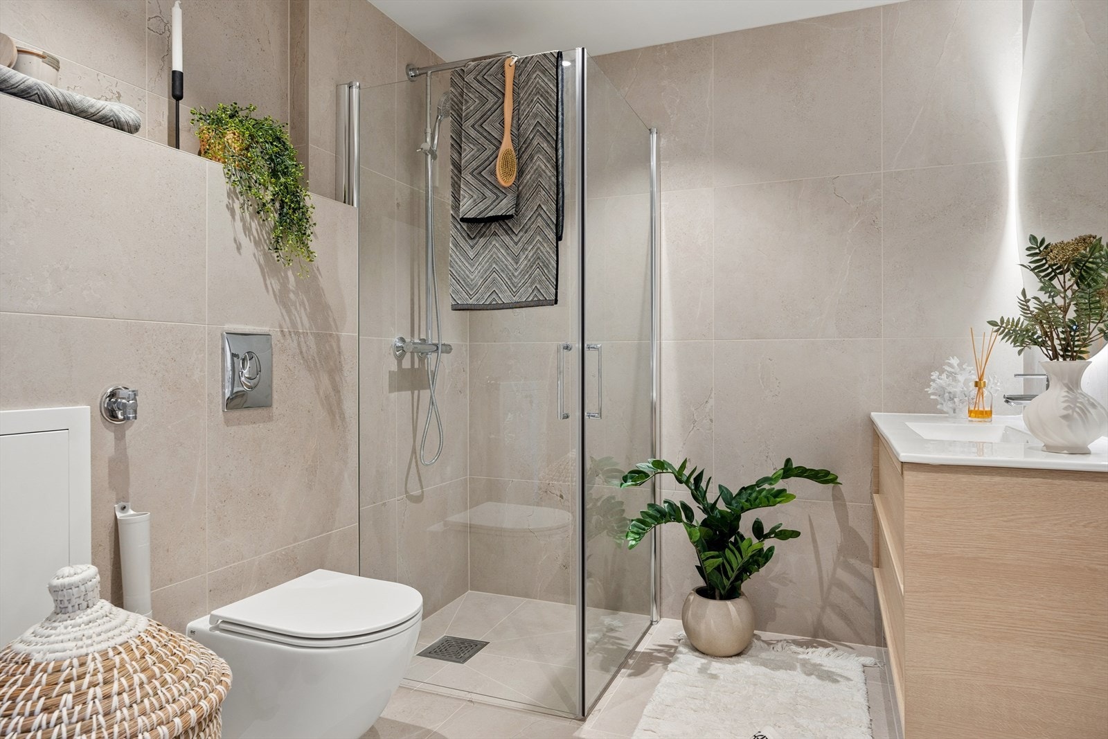 Badet er lekkert flislagt med lyse beige fliser og innredet med servant, toalett, dusjhjørne og opplyst speil. Det er i tillegg opplegg og plass til vaskemaskin. Galleribilde