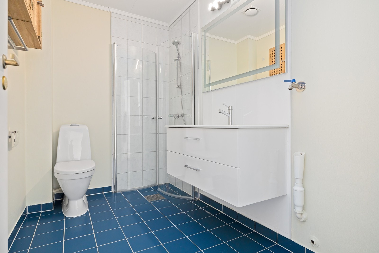 Badet har flislagt gulv, dusjhjørne med glassdører og opplegg for vaskemaskin. Galleribilde