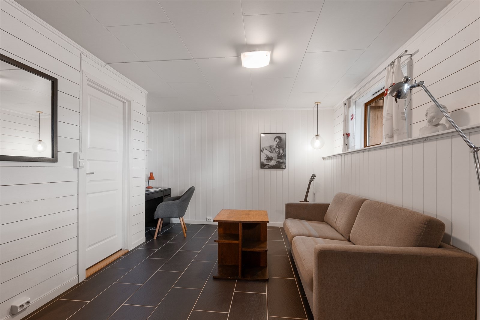 Rommet er innredet med panel på veggene og gir ekstra plass for hobbyaktiviteter eller som en TV-stue for ungdommen. Galleribilde