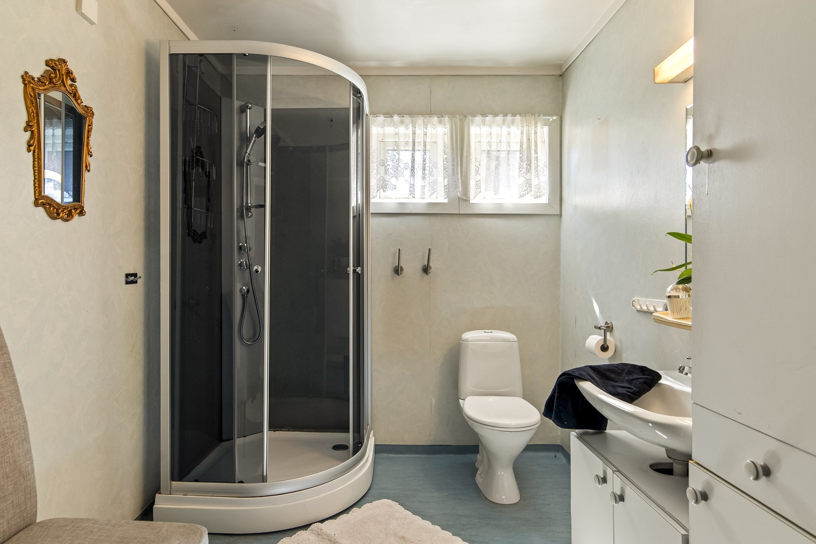 Badet er romslig og innredet med toalett, dusjkabinett, servant i innredning, nyere vvb og opplegg til vaskemaskin Galleribilde