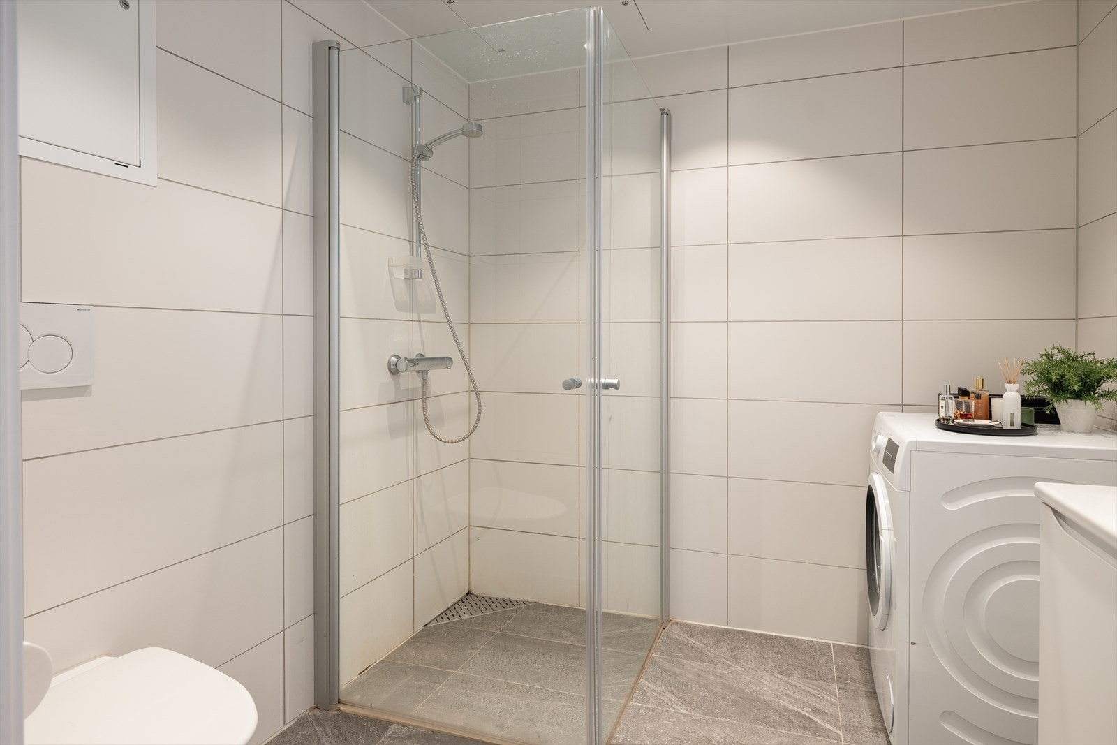 Badet er utstyrt med servant, dusjhjørne med innfellbare dusjdører, vegghengt dusjarmatur, vegghengt toalett og mekanisk avtrekk. Galleribilde