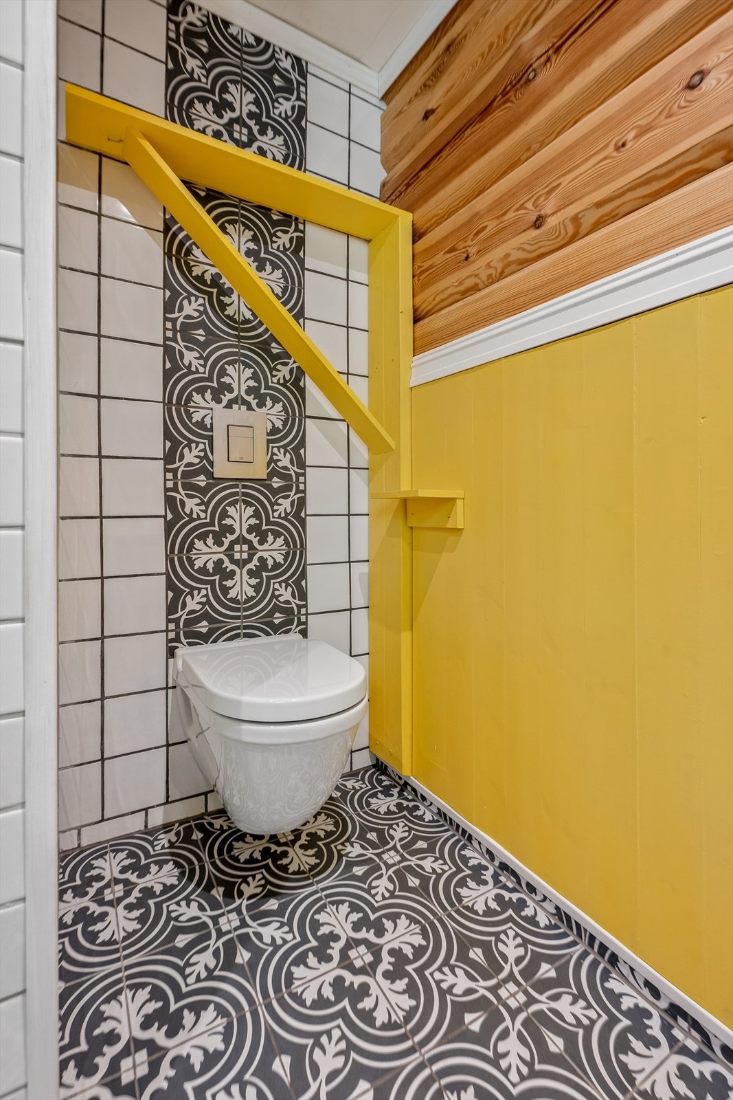 Detalj fra badet som viser kombinasjonen av mønstrede gulvfliser og slette veggfliser. Galleribilde