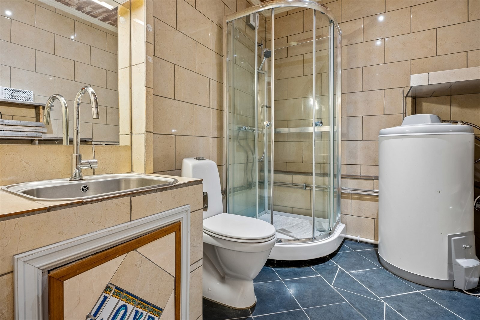 Badet i garasjen er utstyrt med toalett, servant og dusjkabinett. Etablering av bad i garasjen er ikke dokumentert. Galleribilde