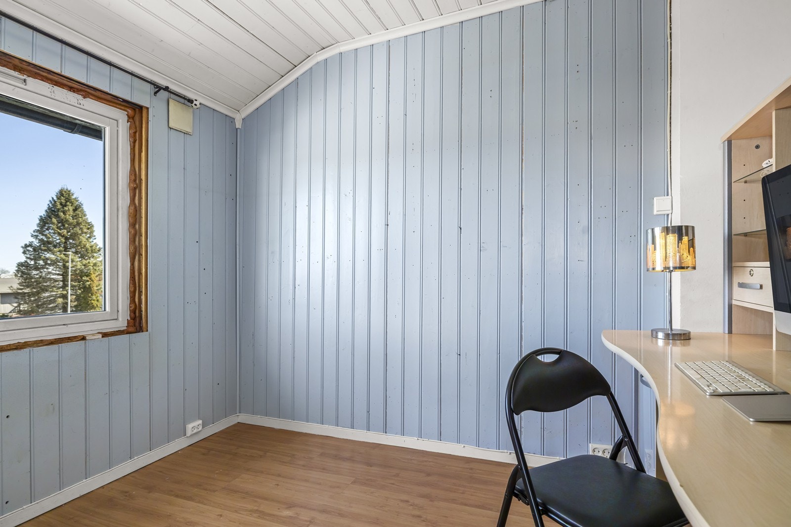 Rommet har panel på veggene og laminat på gulvet. Galleribilde