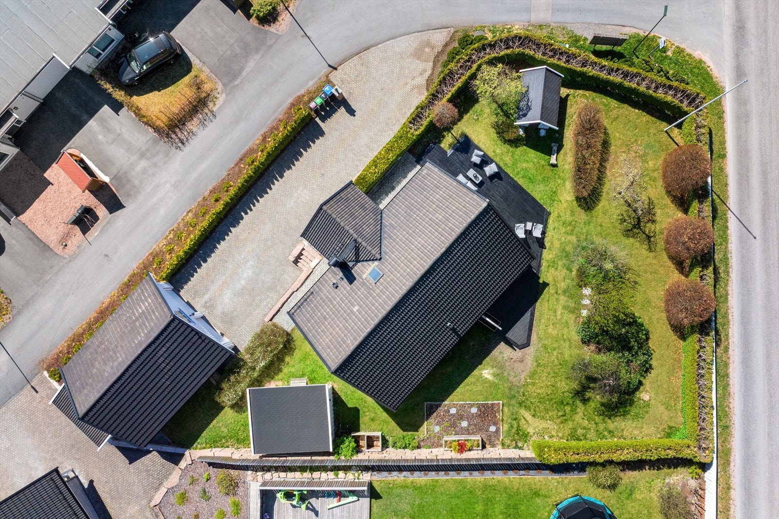 Tomten er pent opparbeidet med fine plenarealer som gir rom for både lek og avslapning, pent innrammet av hekk, busker og variert beplantning som skaper en lun og grønn ramme rundt eiendommen. Galleribilde