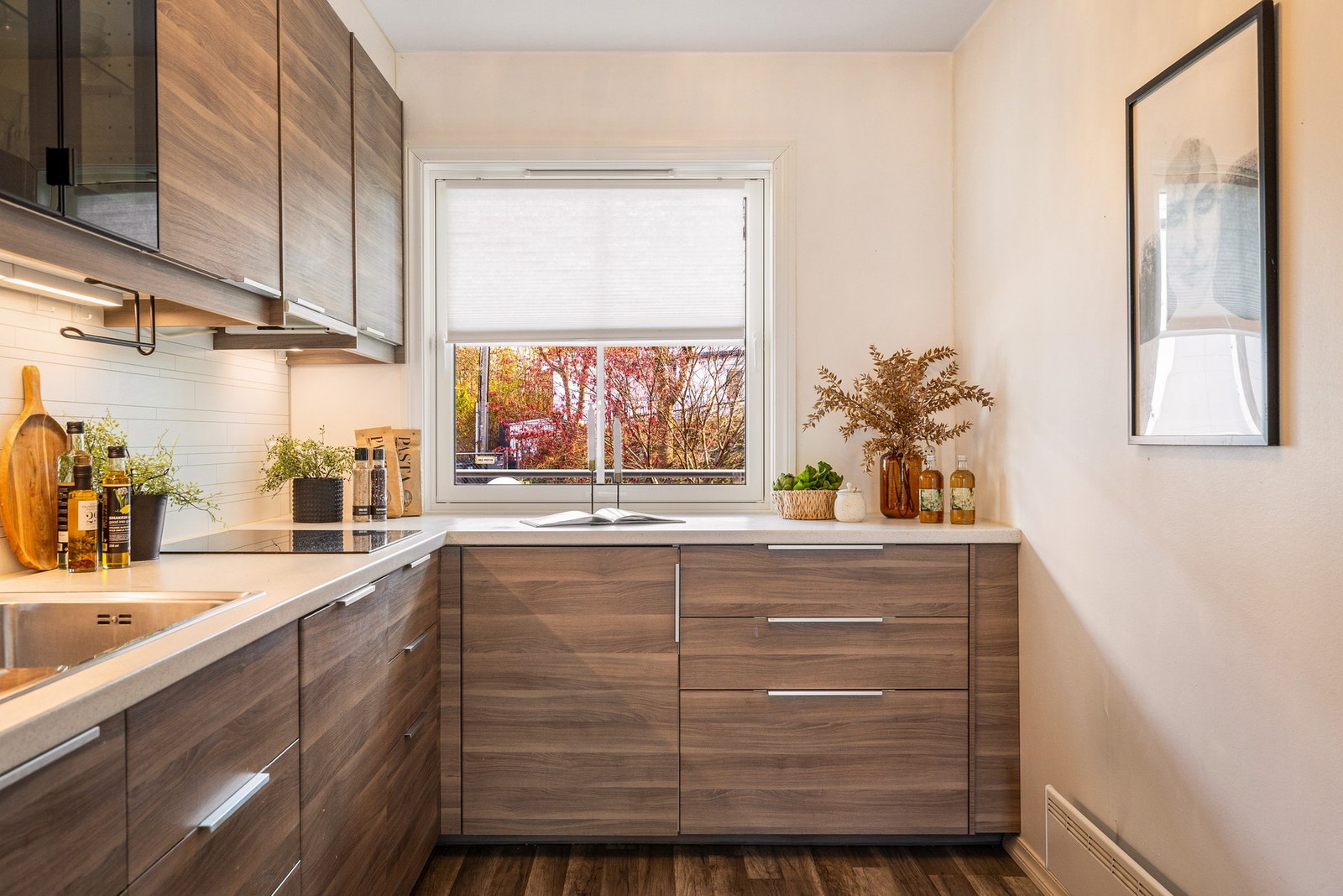 Kjøkkeninnredning med slette fronter, laminat benkeplate og kitchenboard over benkeplaten. Kjøkkenet er utstyrt med stål oppvaskkum og ventilator - Galleribilde