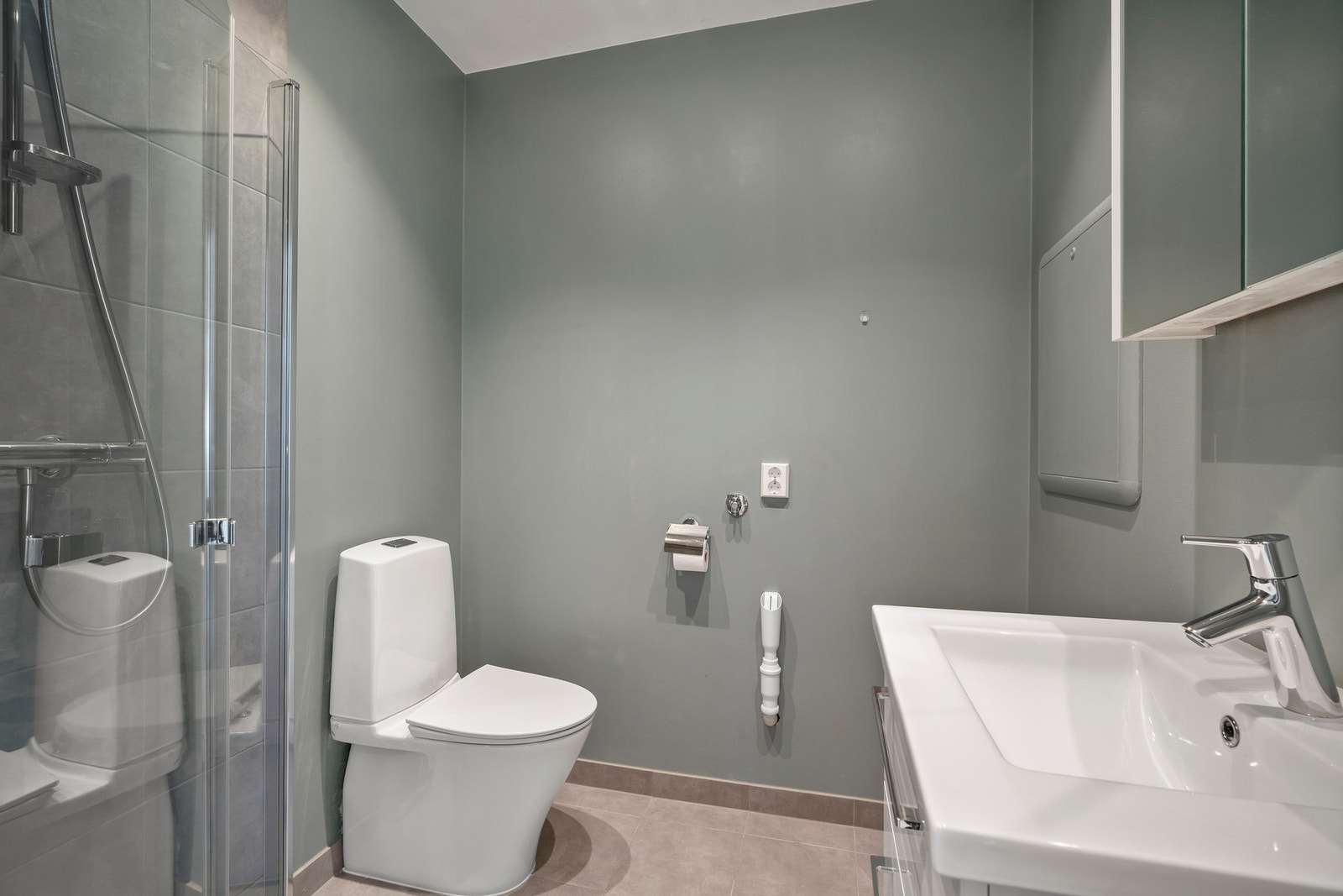 Badet har vegger med malte plater og fliser i dusjsone, malt tak og flislagt gulv med elektriske varmekabler. Galleribilde