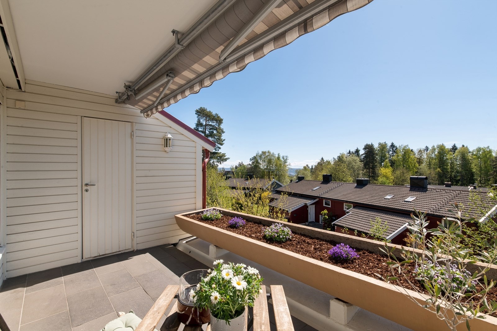 Terrassen har flislagt gulv, rekkverk i form av blomsterkasse i betong samt en praktisk, tilhørende utvendig bod på ca. 2 m². Galleribilde